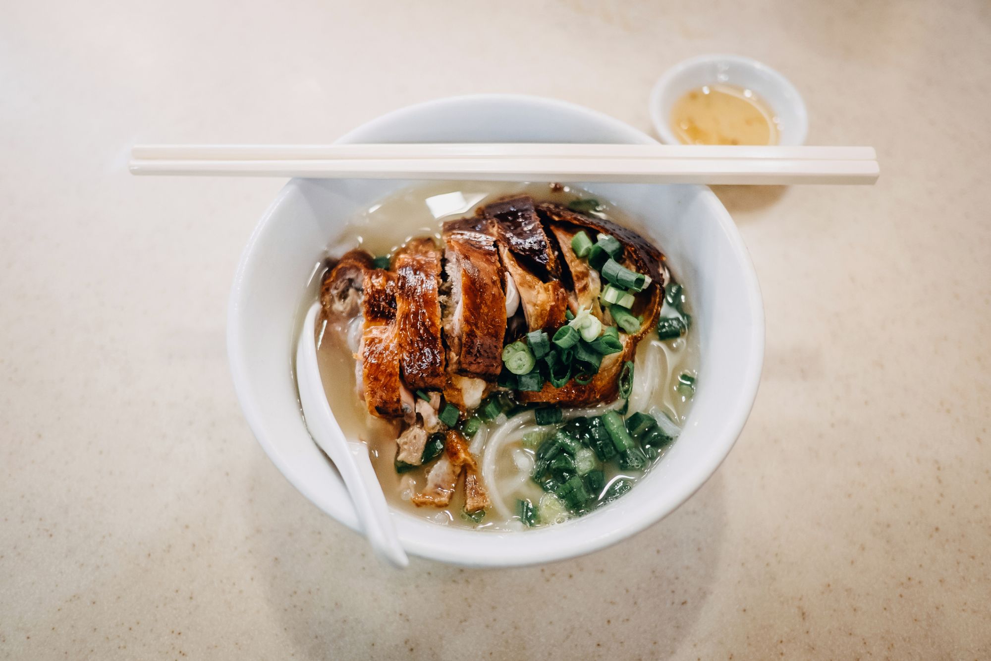 A bowl of roast duck soup noodle freshly served on table in restaurant
