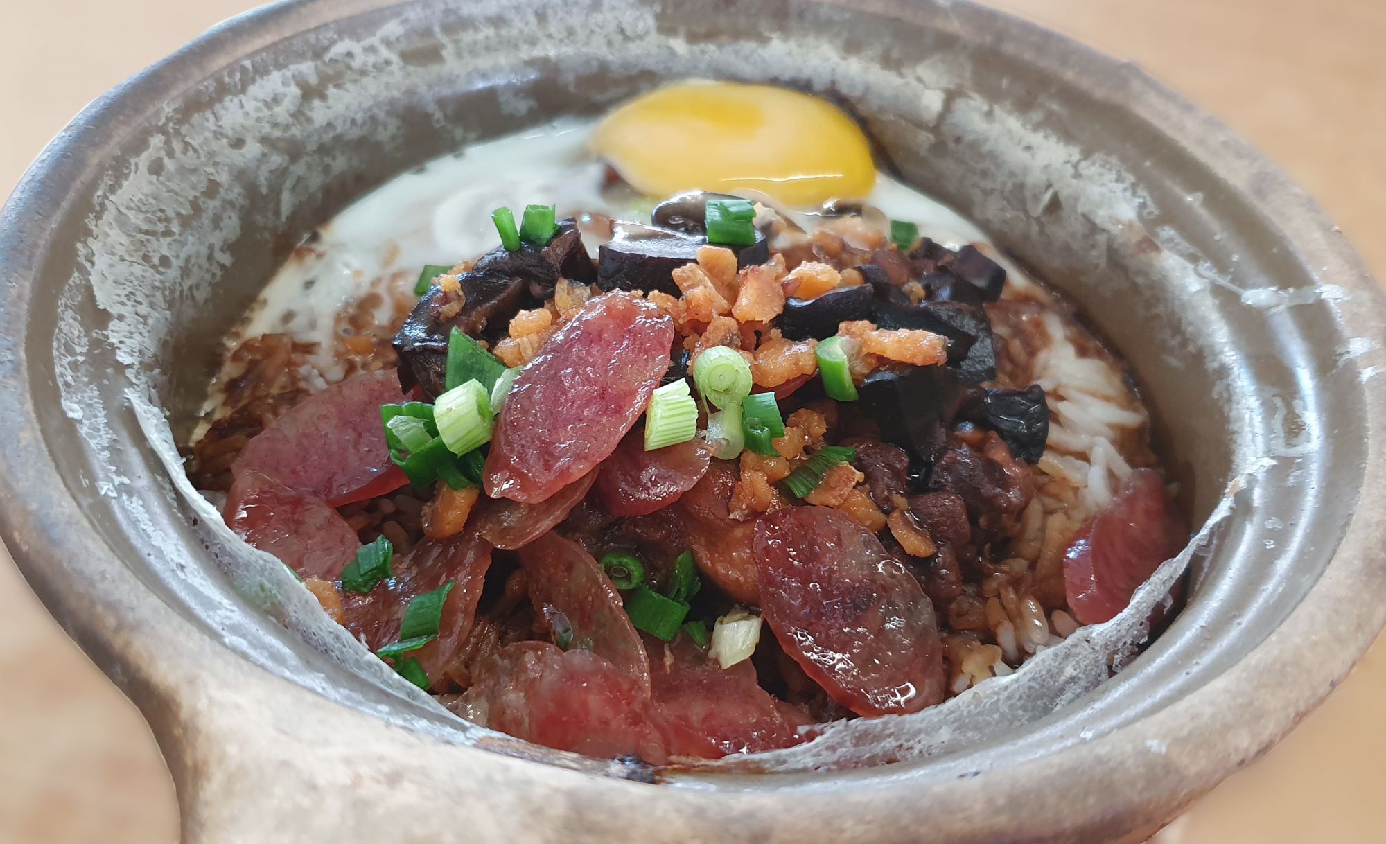 It is served with meat sausage, Shitake mushroom, egg, chicken, minced salted fish. The rice is cooked in the claypot first over a charcoal stove, giving the dish a distinctive flavour and it is garnished with spring onion.