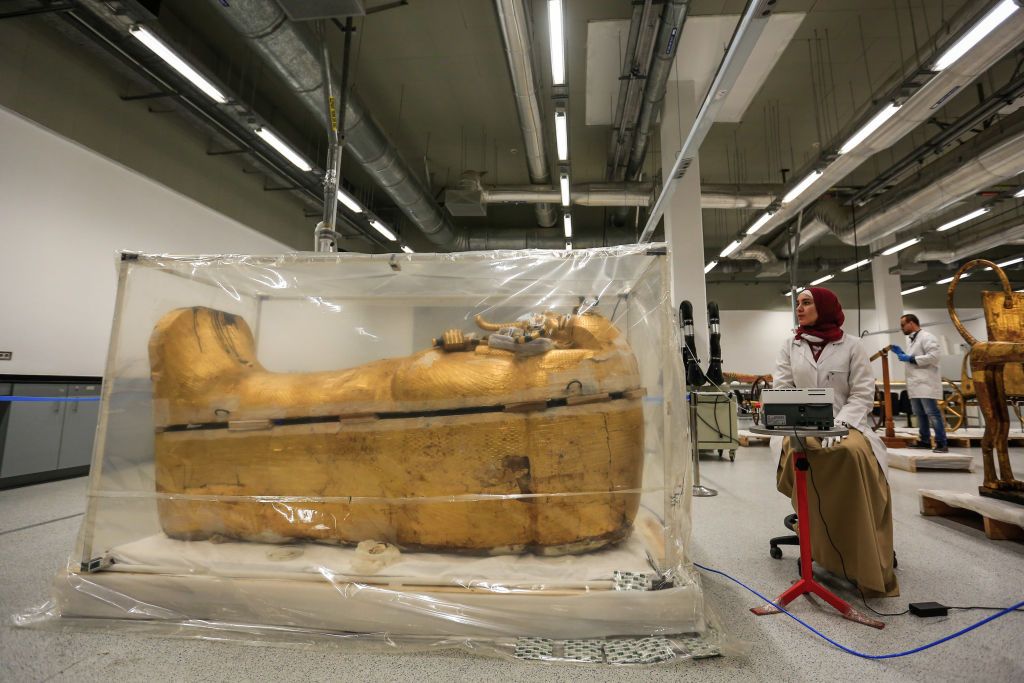 04 August 2019, Egypt, Giza: An Egyptian archeologist works on the gilded coffin of King Tutankhamun during a restoration process, the first since the tomb was discovered in 1922, at the Grand Egyptian Museum. The coffin was transported from King Tutankhamun's tomb at the Valley of the Kings in Luxor to the Grand Egyptian Museum for an eight-month restoration process, before displaying it among his treasured collection at the museum. Photo: Hassan Mohamed/dpa (Photo by Hassan Mohamed/picture alliance via Ge