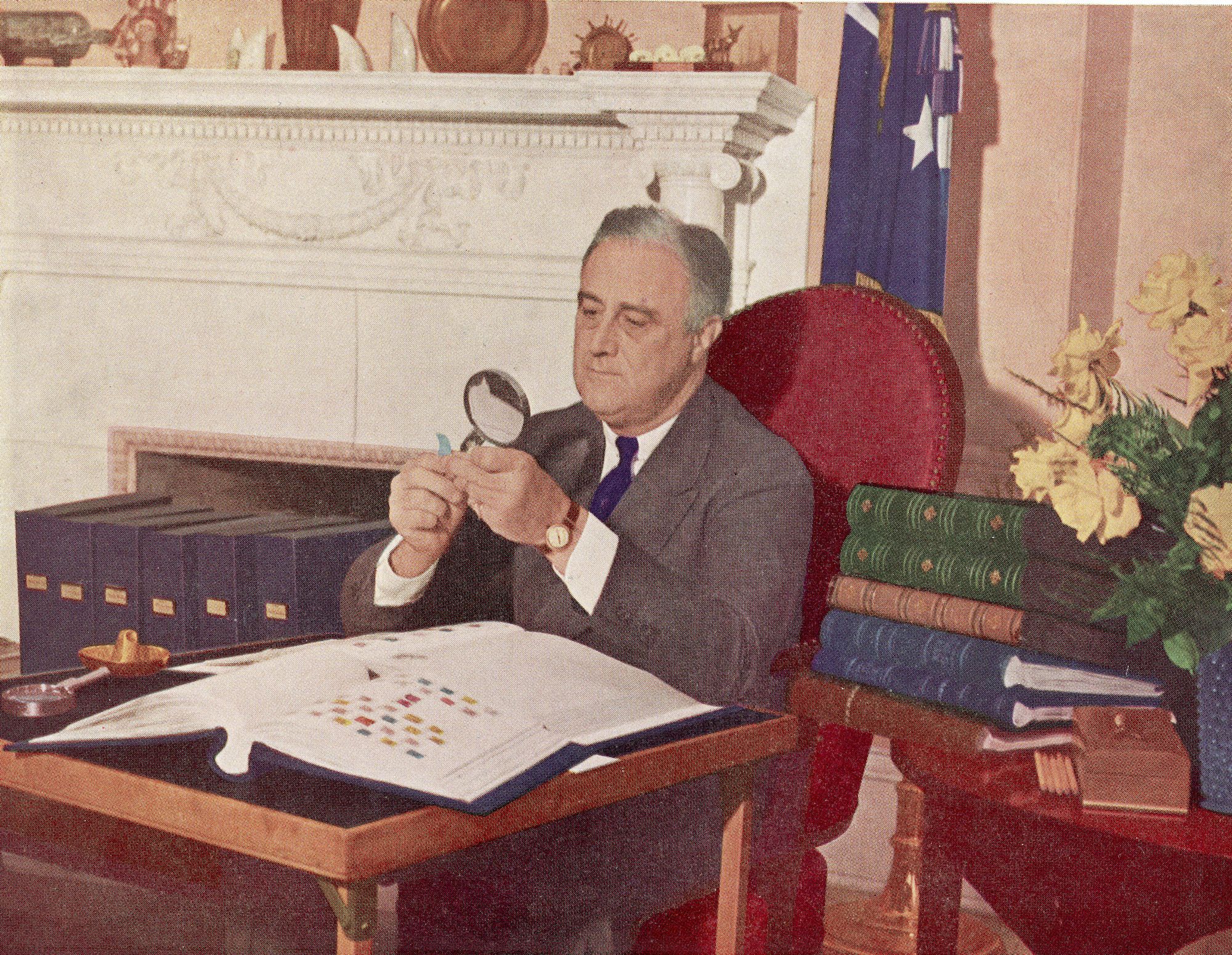 US President Franklin Delano Roosevelt (1882 - 1945) holds a stamp under a magnifying glass while seated at his desk with his stamp collection, Washington, DC, circa 1944. (Photo by Hulton Archive/Getty Images)