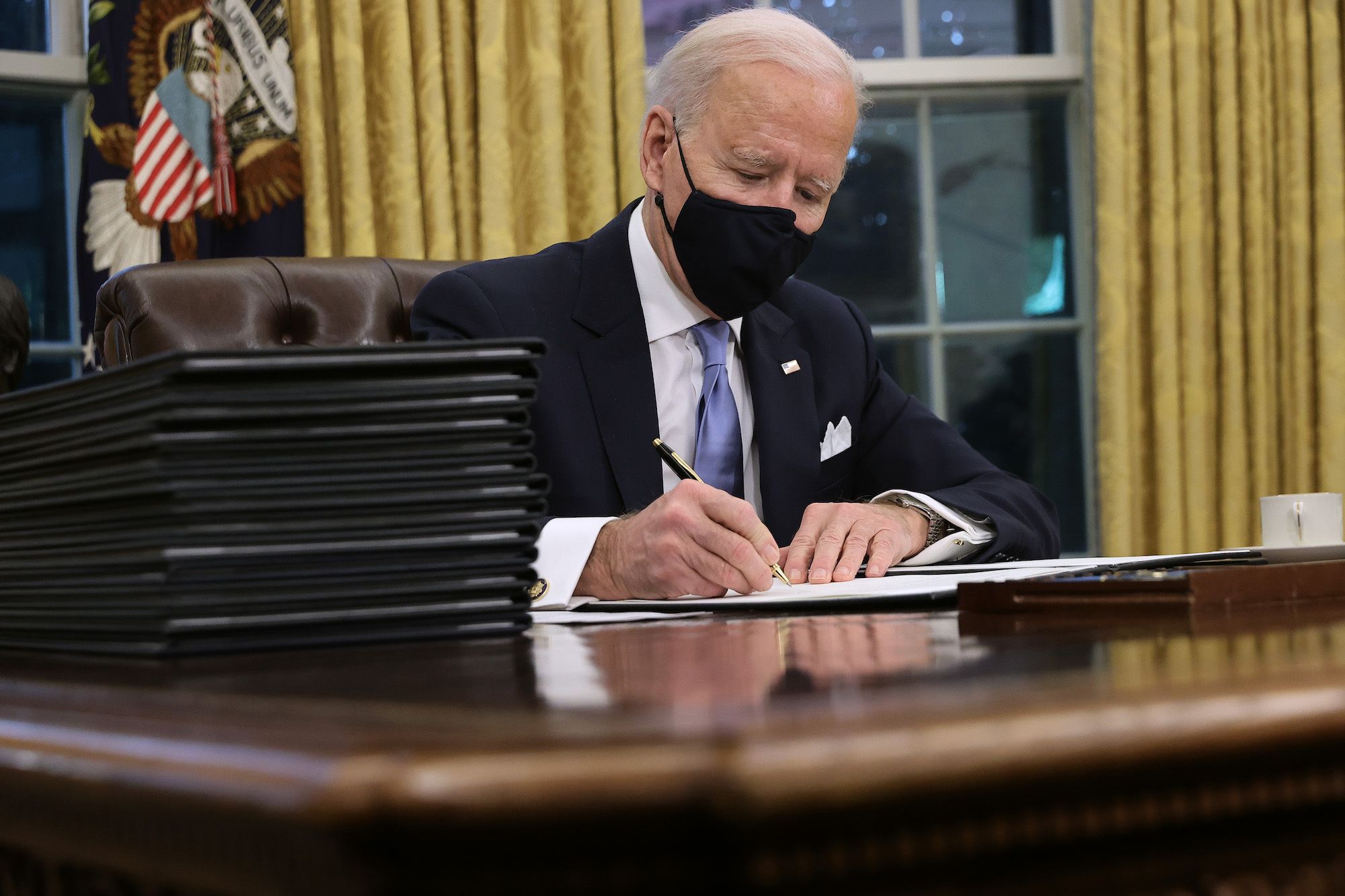 WASHINGTON, DC - JANUARY 20: U.S. President Joe Biden prepares to sign a series of executive orders at the Resolute Desk in the Oval Office just hours after his inauguration on January 20, 2021 in Washington, DC. Biden became the 46th president of the United States earlier today during the ceremony at the U.S. Capitol. (Photo by Chip Somodevilla/Getty Images)