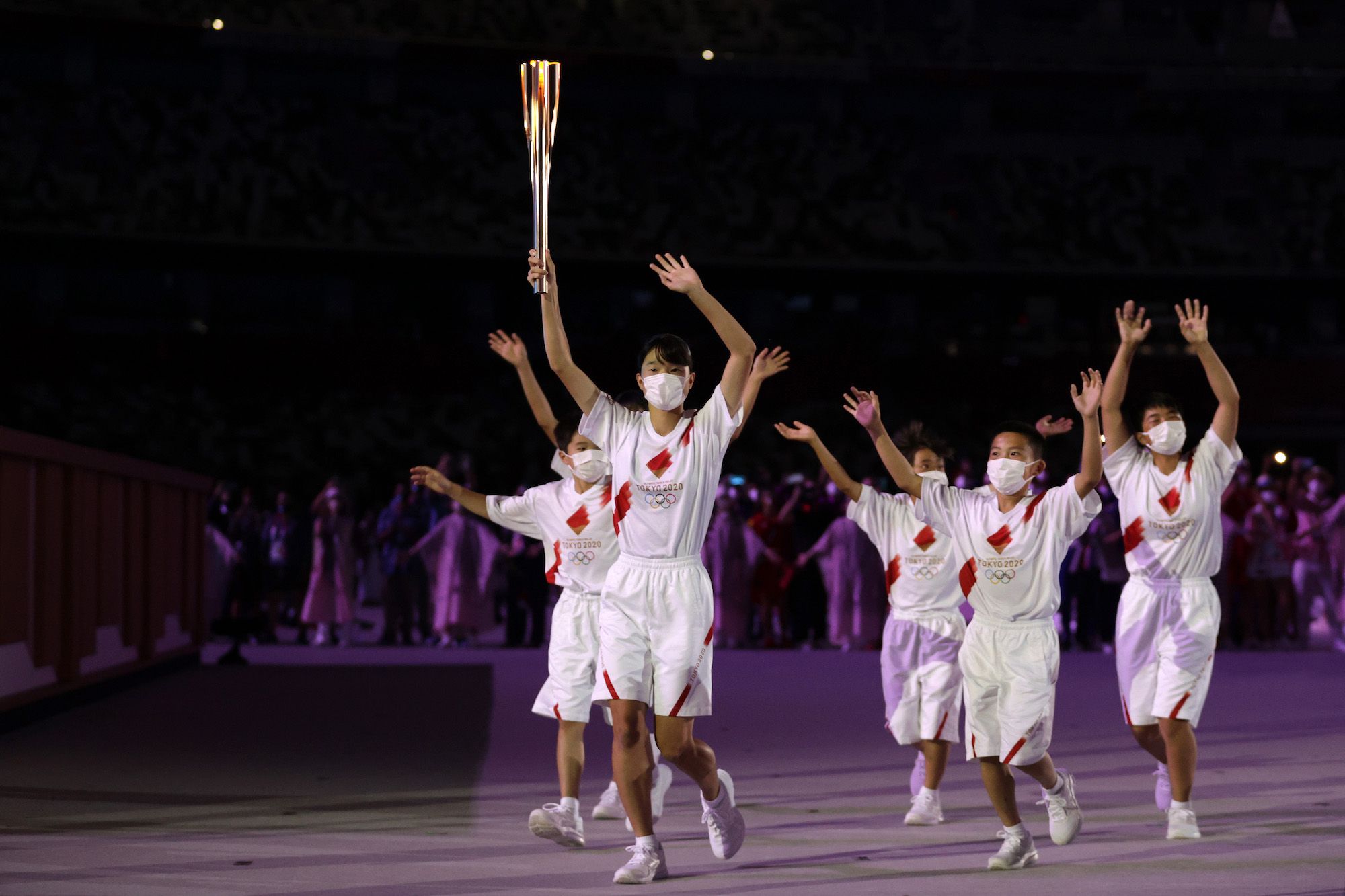 TOKYO, JAPAN - JULY 23: The torch carriers enter the stadium with the Olympic torch during the Opening Ceremony of the Tokyo 2020 Olympic Games at Olympic Stadium on July 23, 2021 in Tokyo, Japan. (Photo by Hannah McKay - Pool/Getty Images)