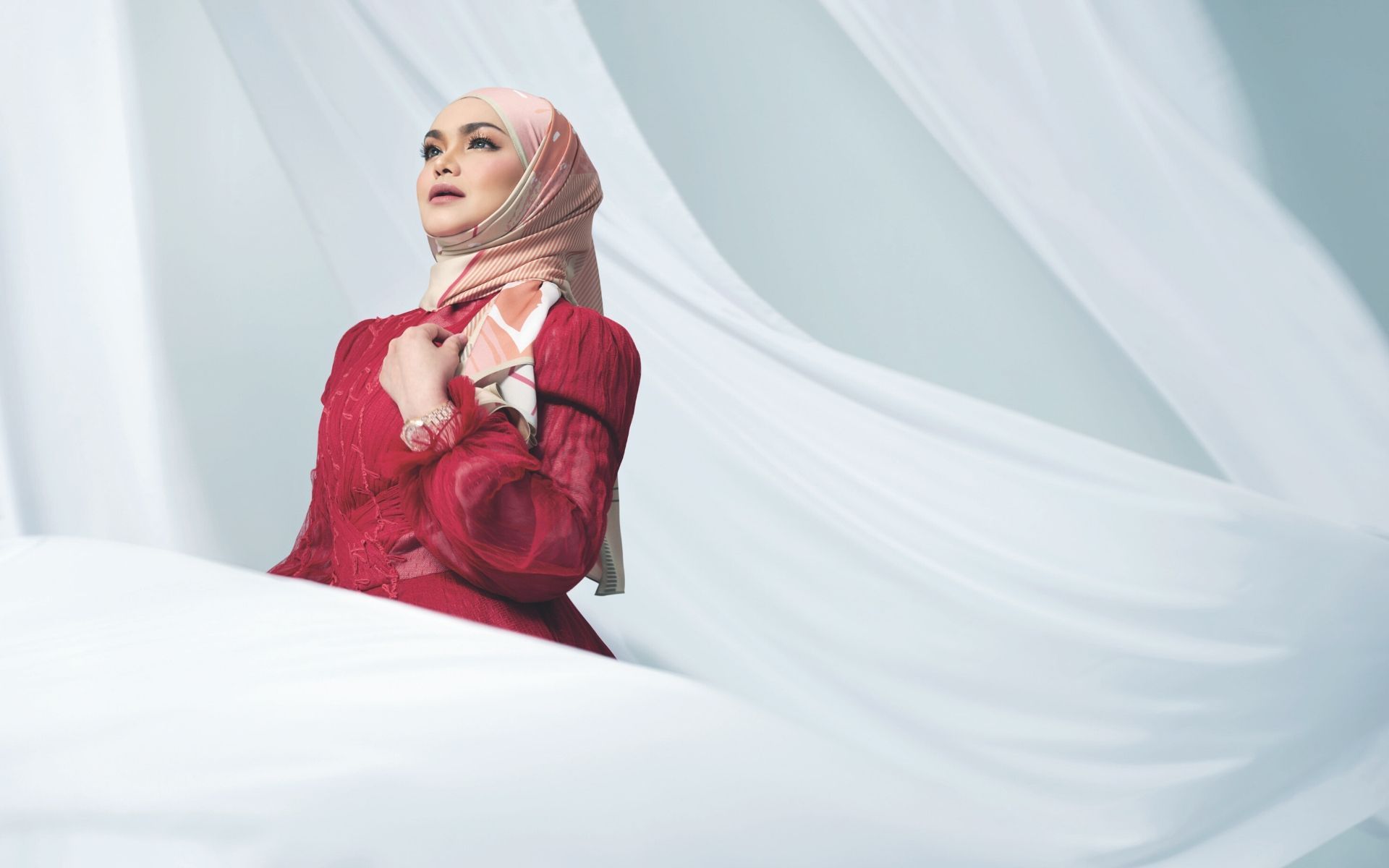 A custom Fiziwoo red dress embroidered with with her songs' lyrics, a headscarf from Galeri Ariani and a Royal Oak Self Winding gold watch by Audemars Piguet
