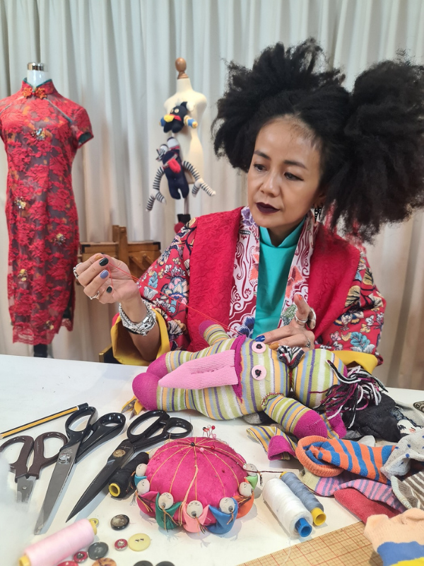 Melinda Looi with a thread and needle, ready to teach a class on how to make ox puppets