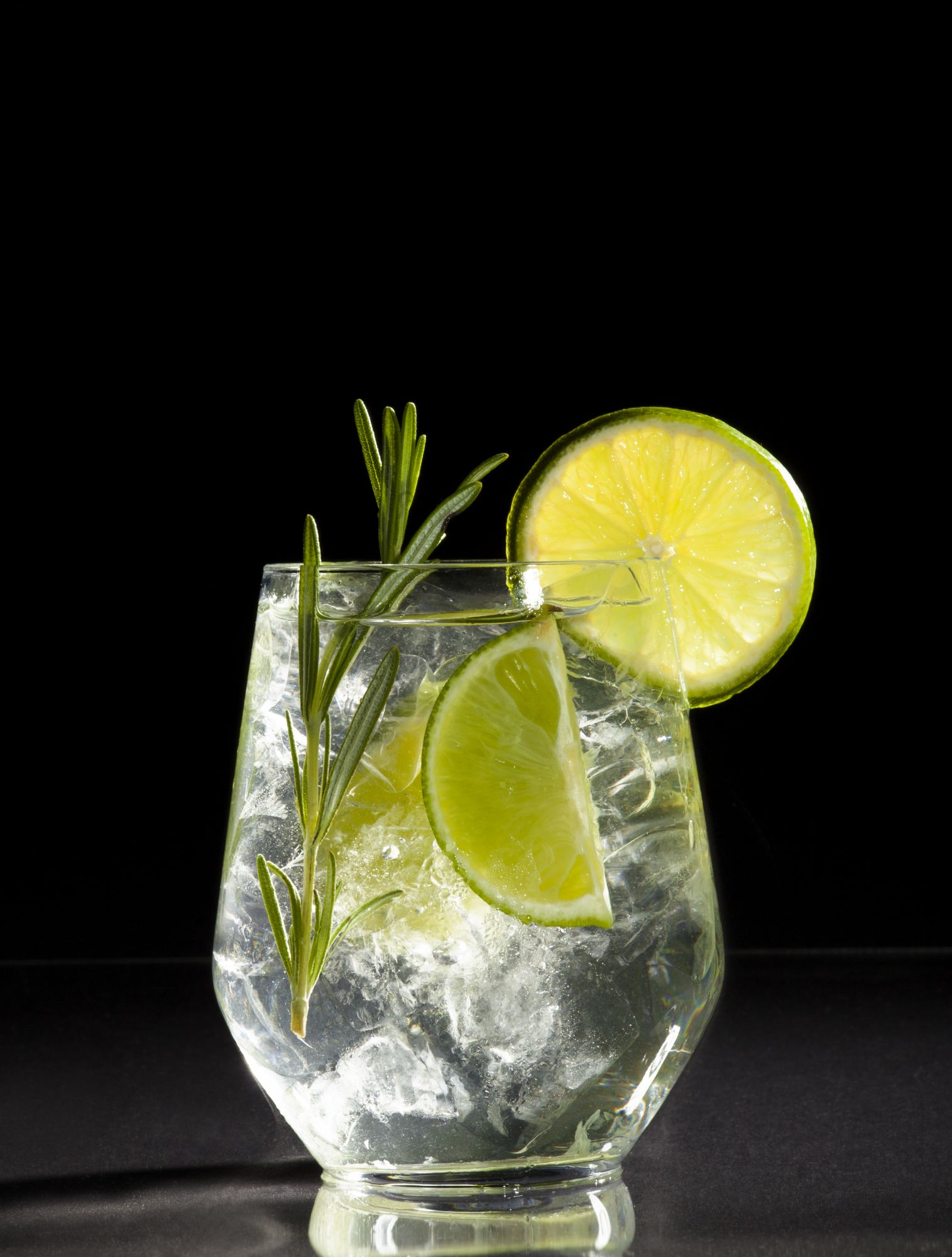 Glass with alcoholic drink with lime and ice on a black background.