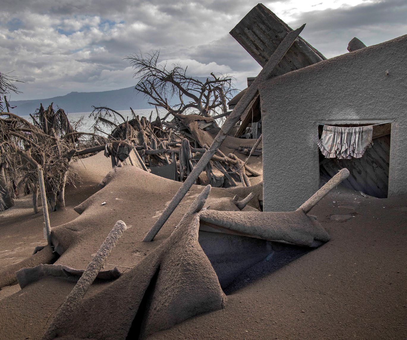 TAAL VOLCANO ISLAND, PHILIPPINES - JANUARY 14: Houses near Taal Volcano's crater are seen buried in volcanic ash from the volcano's eruption on January 14, 2020 in Taal Volcano Island, Batangas province, Philippines. The Philippine Institute of Volcanology and Seismology raised the alert level to four out of five, warning that a hazardous eruption could take place anytime, as authorities have evacuated tens of thousands of people from the area. An estimated $10 million worth of crops and livestock have been