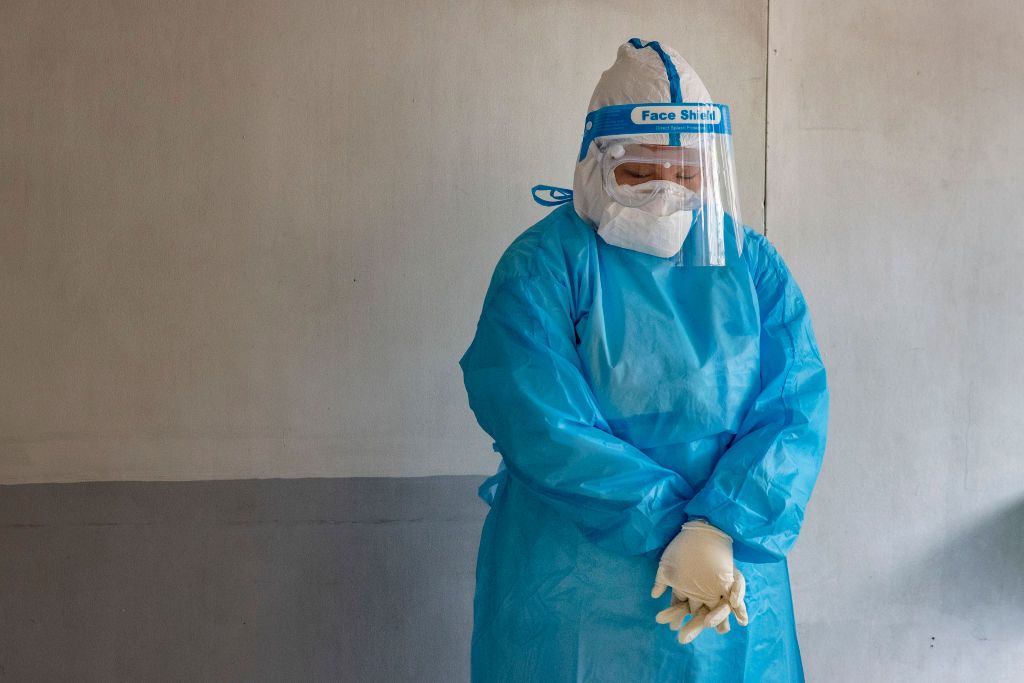 MANILA, PHILIPPINES - AUGUST 6: A medical worker wearing personal protective equipment bows her head in prayer as a priest blesses a hospital on August 6, 2020 in Manila, Philippines. President Rodrigo Duterte has reimposed a strict lockdown in capital Manila and surrounding provinces as the country continues to struggle with rising coronavirus infections which has breached 100,000 cases. Duterte's move came after nearly 100 medical organizations representing 80,000 doctors and a million nurses called for t
