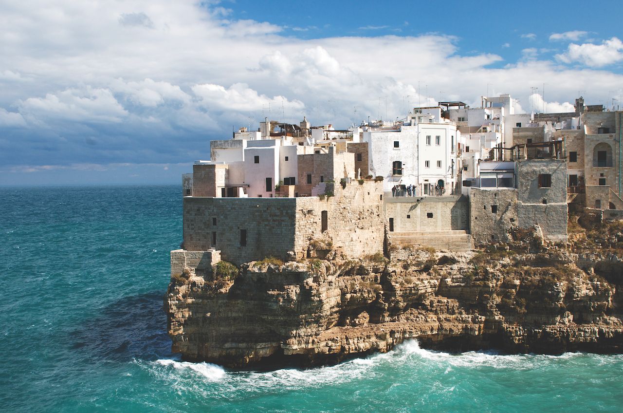 Polignano a Mare, Puglia, Italy. Rocky outcrop with white washed houses overlooking the Mediterranean sea. Dramatic coastline southern Italy.