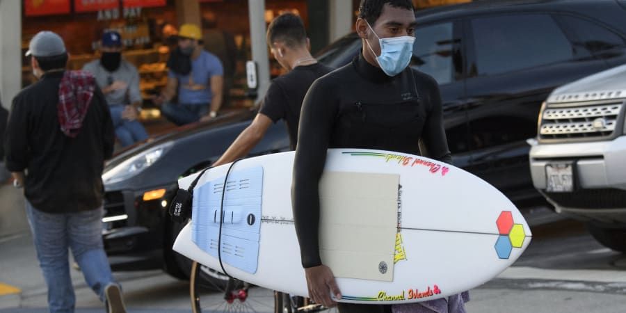 Surfers wear face masks to protect themselves from COVID-19