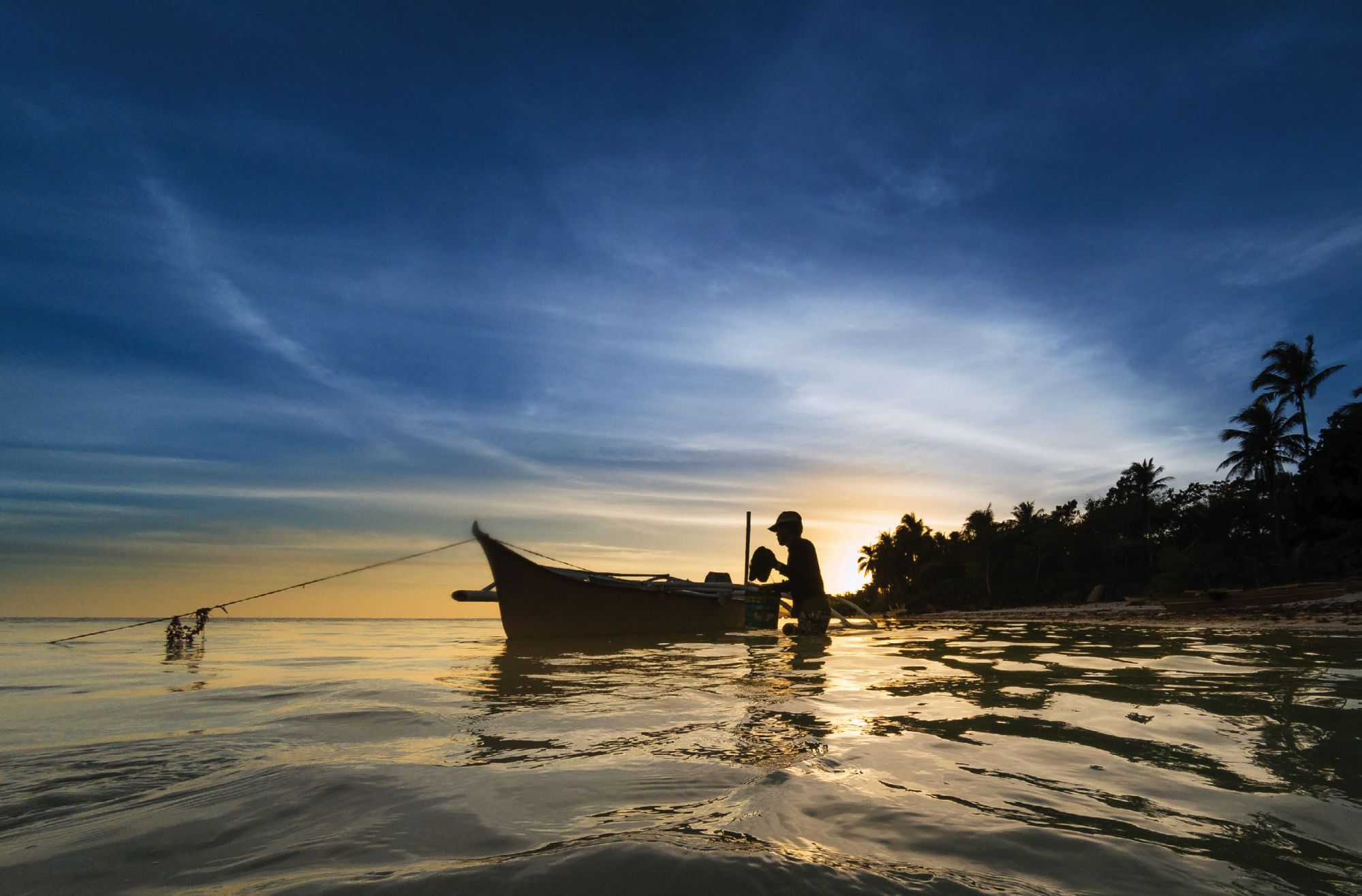 At sunset, a fisherman prepares his outrigger boat for a night out into the sea in Anda, Bohol