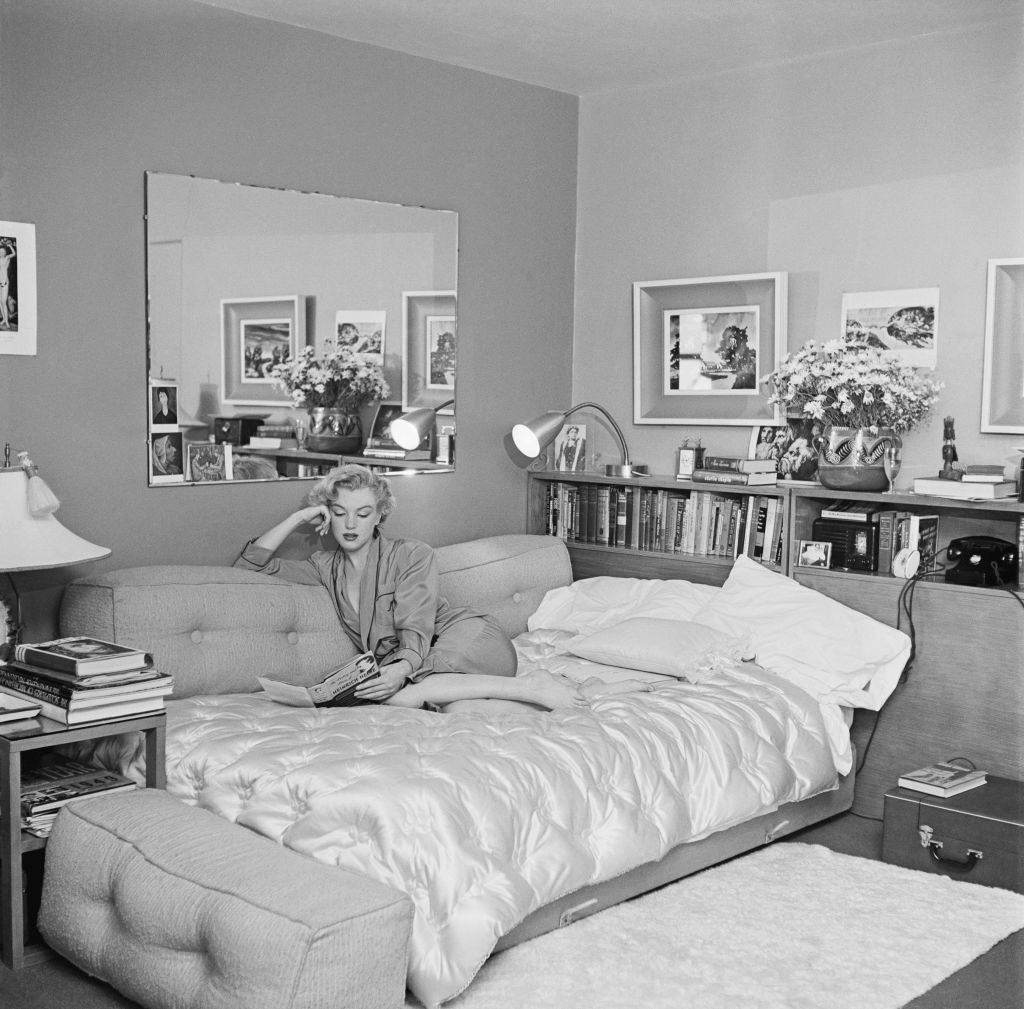 American actress Marilyn Monroe (1926 - 1962) relaxes on a sofa bed, circa 1951. The book she is reading is 'The Poetry and Prose of Heinrich Heine'. (Photo by Archive Photos/Getty Images)