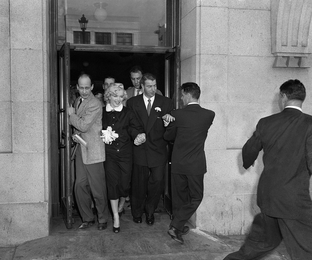 (Original Caption) 1/17/1954- San Francisco, CA: "Mr and Mrs." Film star Marilyn Monroe and former Yankee great Joe Di Maggio press through a crowd of newsmen after their marriage in the office of Municipal Judge Charles Peery in San Francisco City Hall January 14. They were wed in a simple ceremony from which newsmen were excluded. DiMaggio said they planned a ten-day honeymoon.