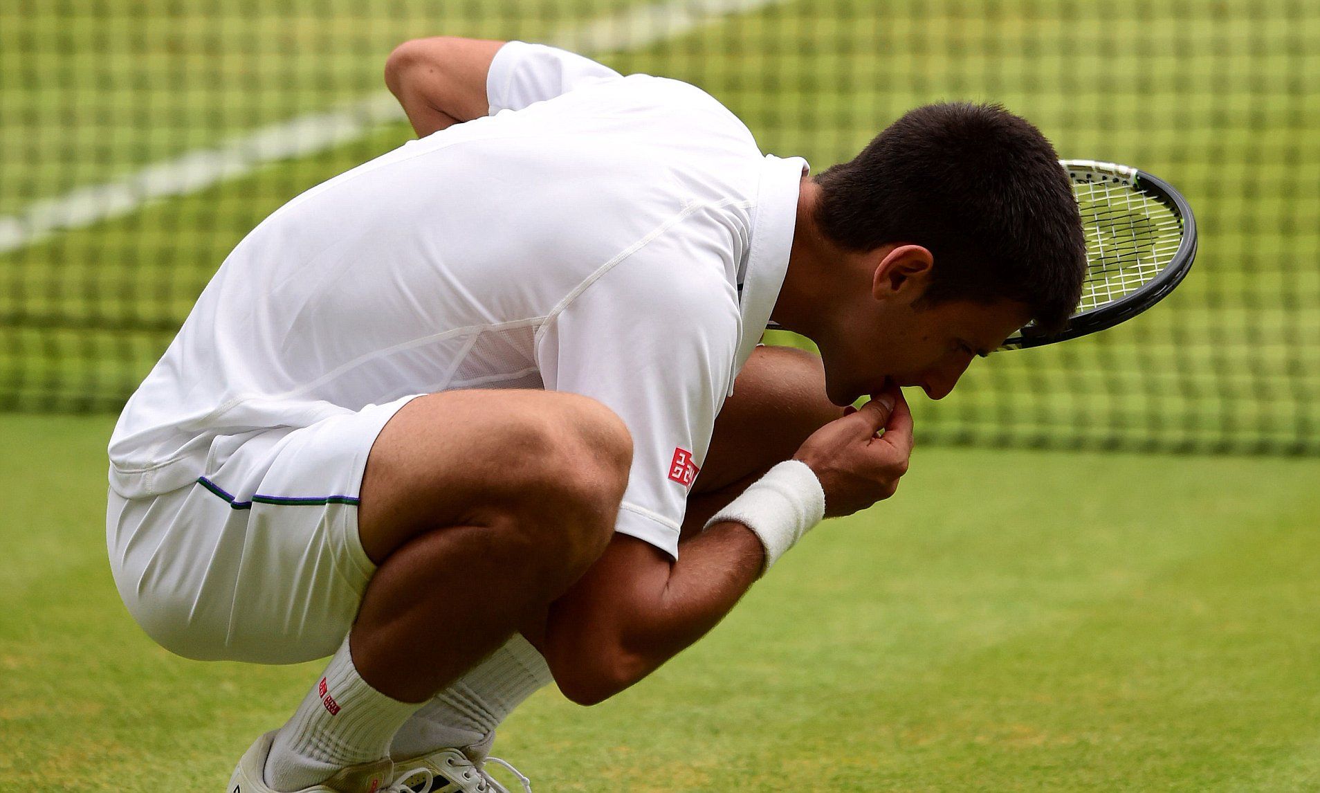 Novak Djokovic eats grass off the court after beating Roger Federer in the Mens Singles Final on day Thirteen of the Wimbledon Championships at the All England Lawn Tennis and Croquet Club, Wimbledon. PRESS ASSOCIATION Photo. Picture date: Sunday July 12, 2015. See PA Story TENNIS Wimbledon. Photo credit should read: Dominic Lipinski/PA Wire. RESTRICTIONS: Editorial use only. No commercial use without prior written consent of the AELTC. Still image use only - no moving images to emulate broadcast. No supe