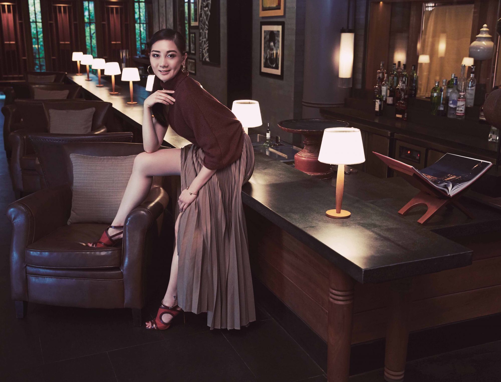 Knitted turtleneck top by Brunello Cucinelli; pleated skirt by Céline; linen canvas and calfskin sandals by Hermès; Studdy hoop earrings and bracelet, both by Louis Vuitton