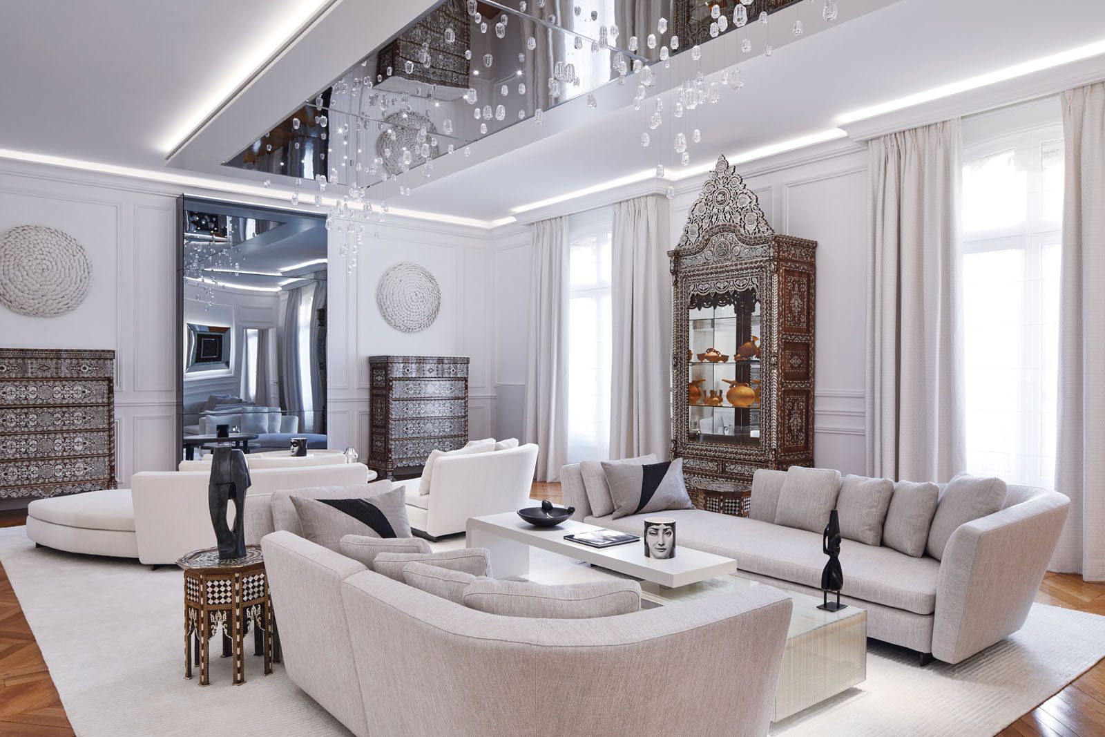 The living room features antique dressers next to the custom-made chrome fireplace and Minotti sofas