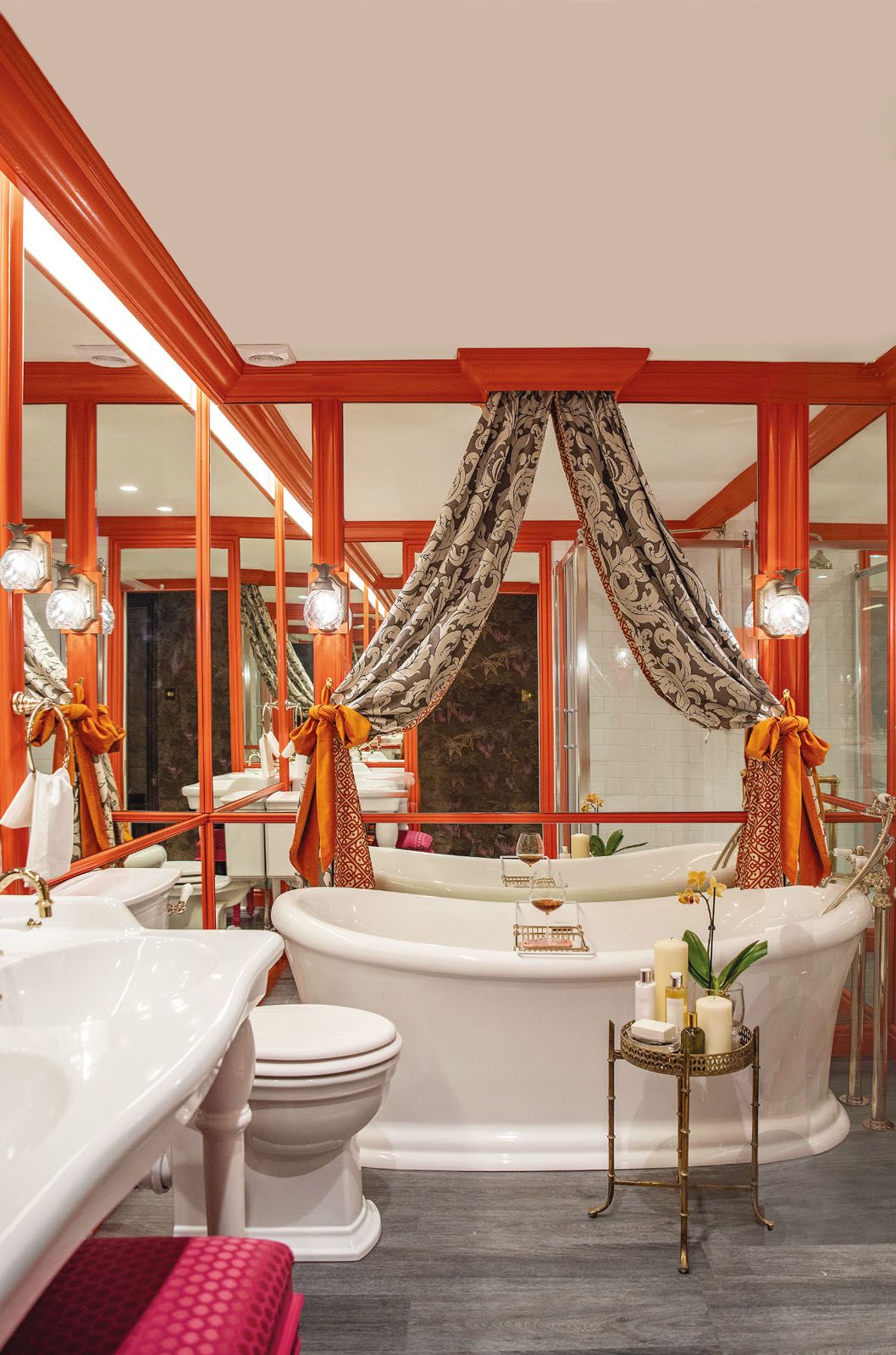 The silk-tie curtains and mirrored walls complete the bathroom’s glamorous look;