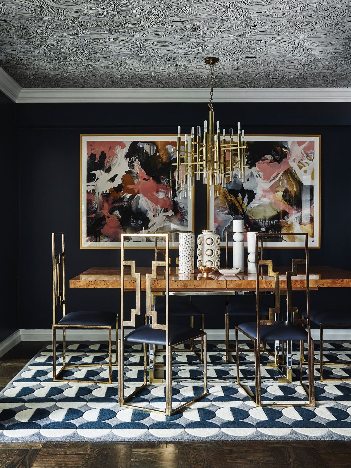 The dining room features vintage brass chairs, a Gaetano Sciolari light, a geometric rug and abstract paintings by Scott Petrie