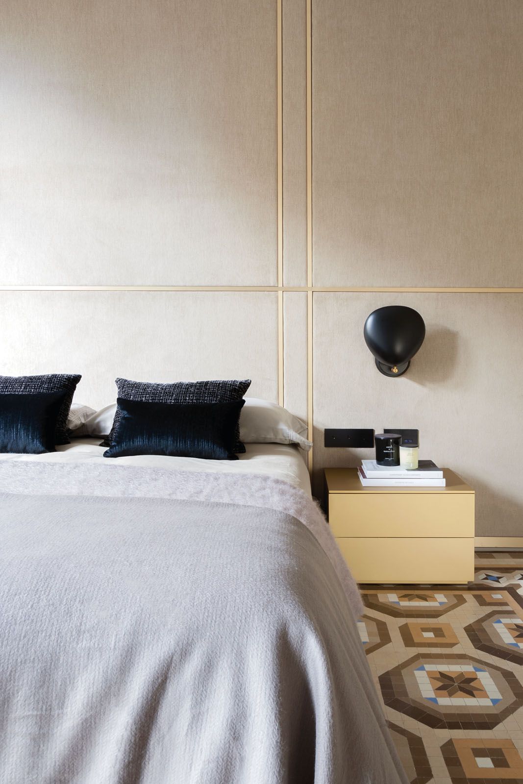 The bedside table was selected to match the brass frame on the upholstered headboard
