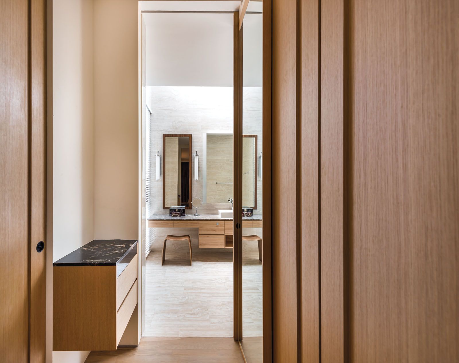 The minimalist bathroom features wood cladding, natural stone and sleek mirrors