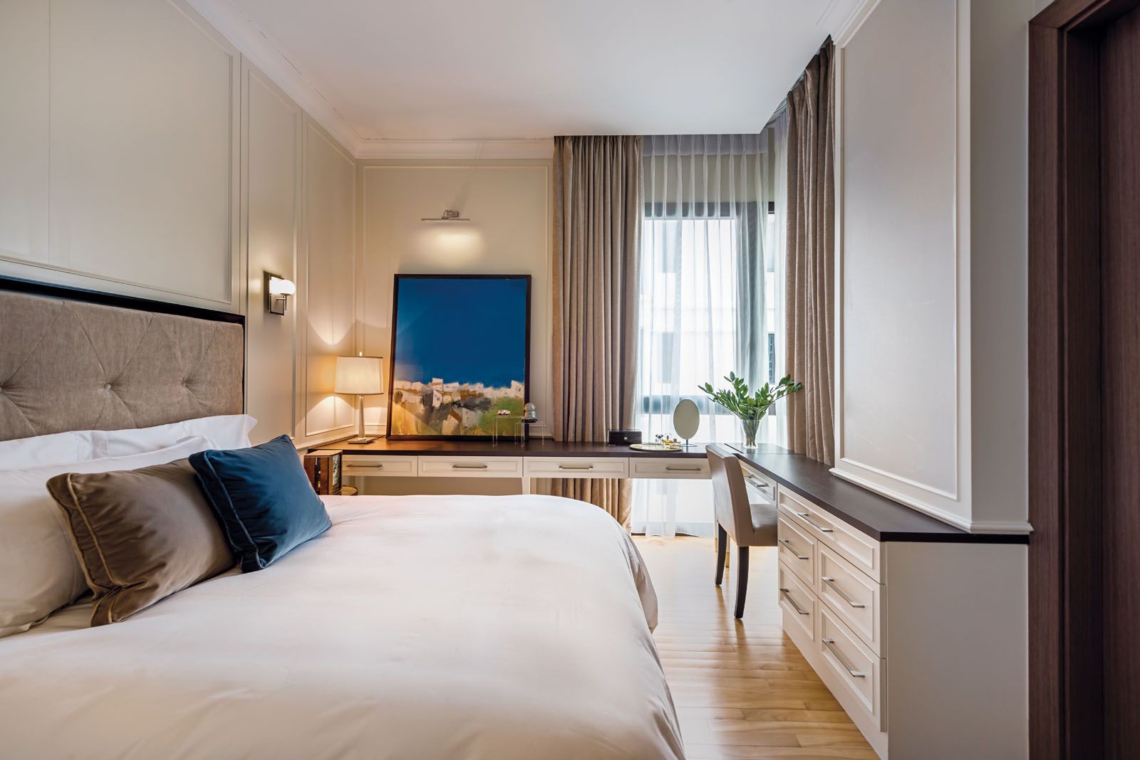 The daughter’s bedroom features white wainscoting panels and a tranquil mix of taupe and navy tones