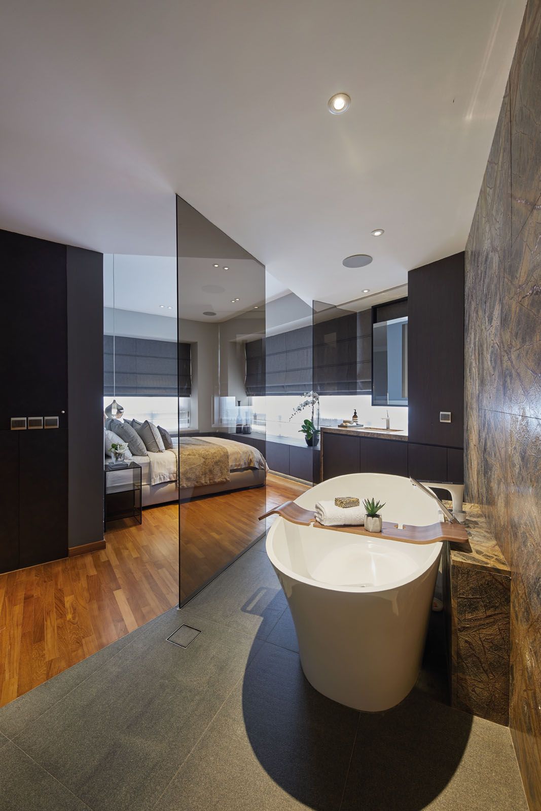 Tinted glass panels separate the bedroom area from the bathroom