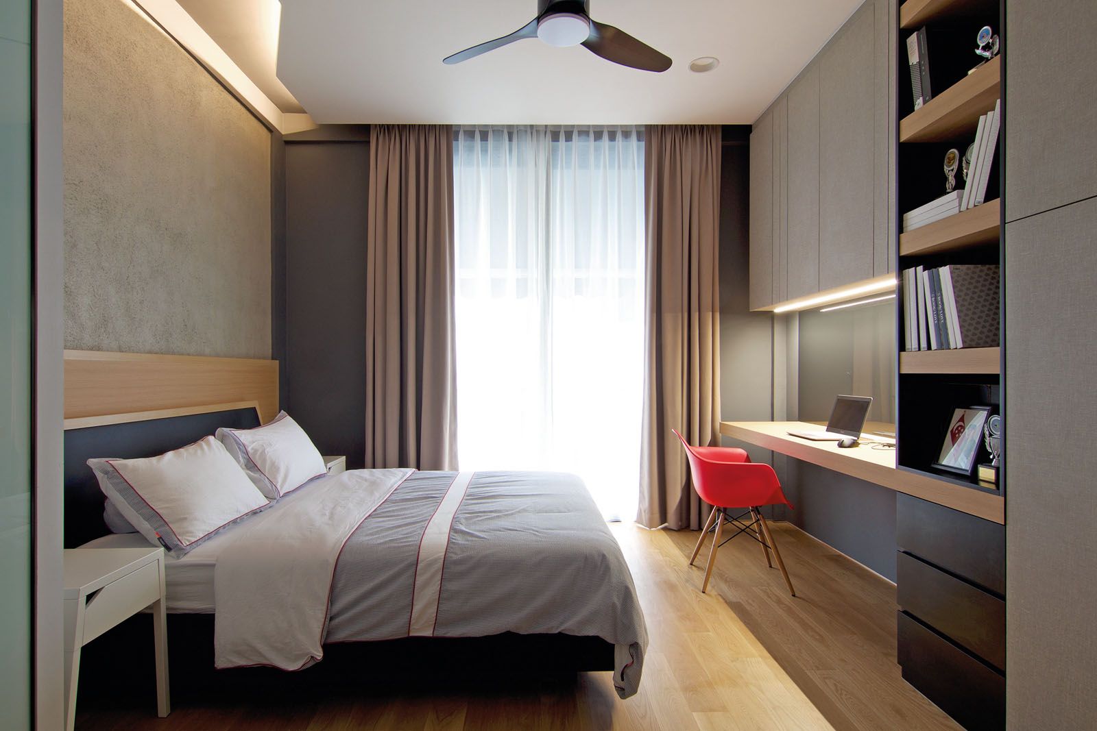 A red armchair holds court in the neutral bedroom