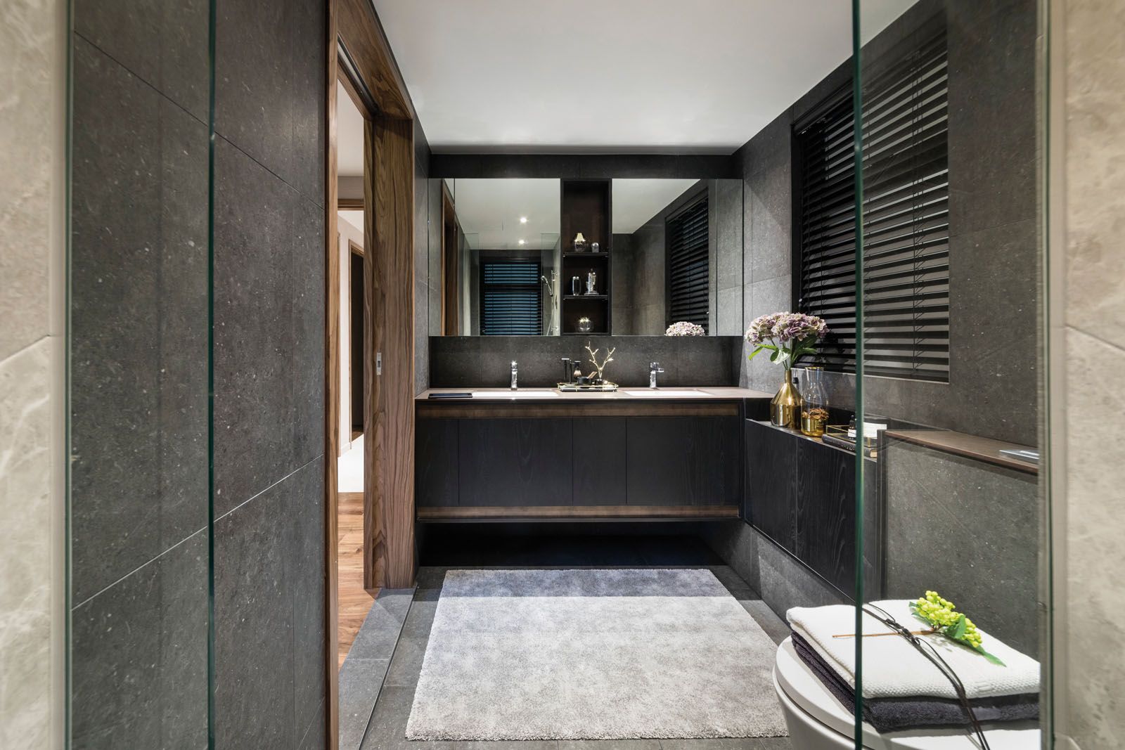 The monochromatic material palette of the master bedroom is also conveyed in its ensuite bathroom