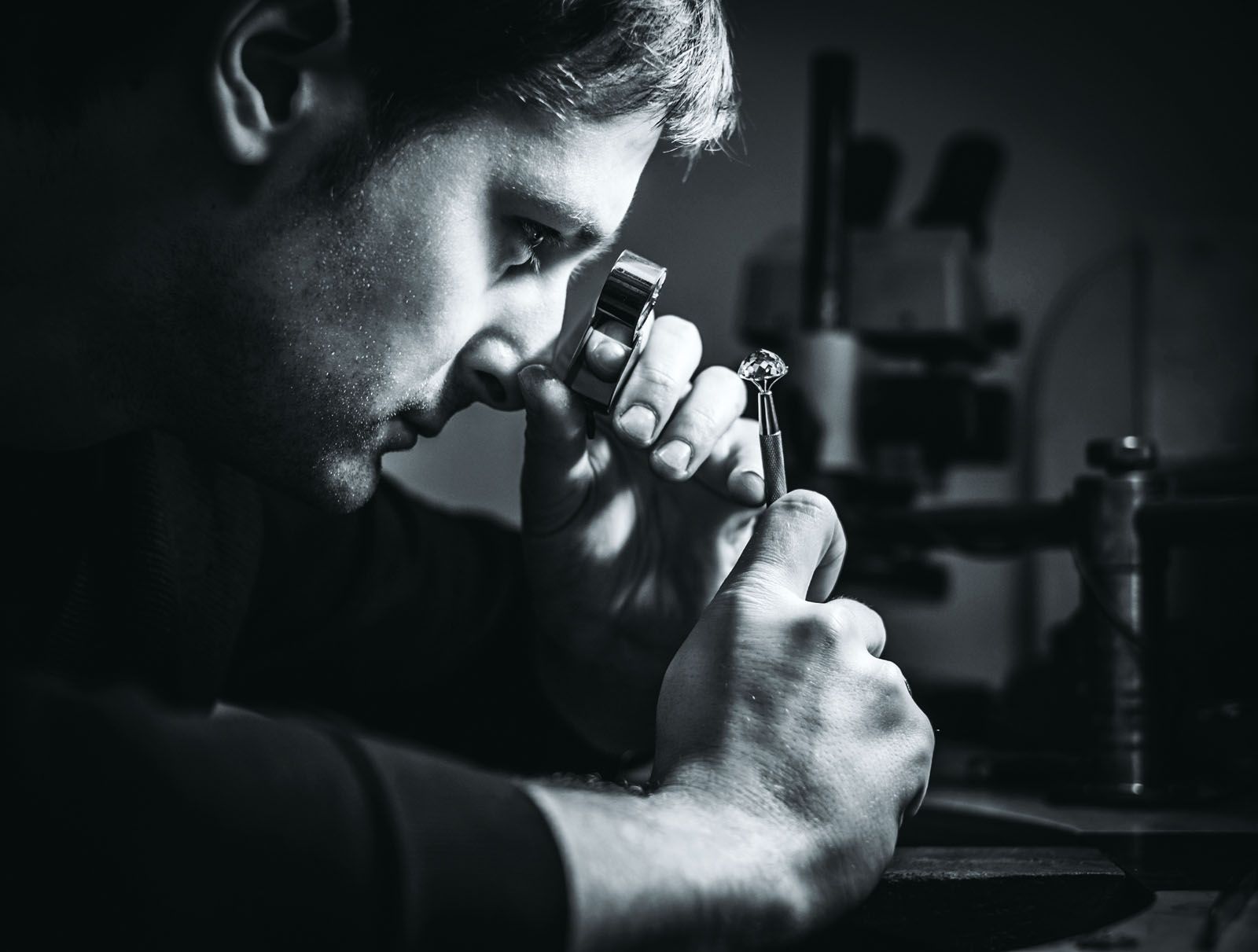 Jeweller looking at the ring through microscope in a workshop