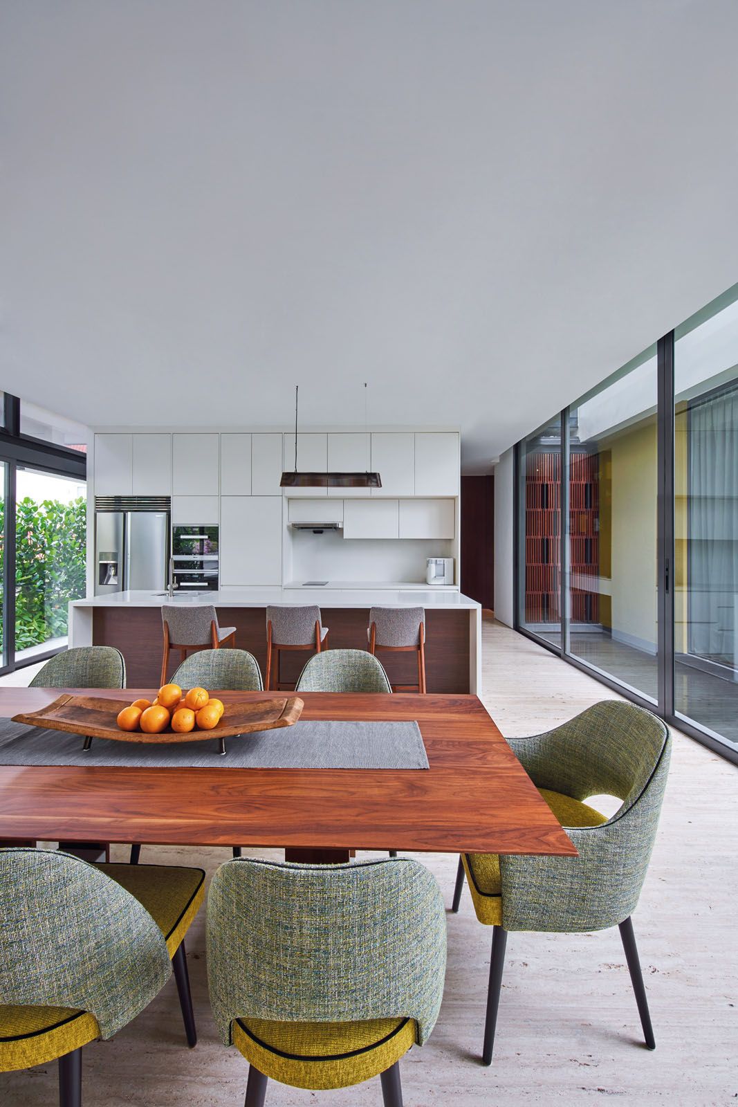 The kitchen features a dining table from Porada and a colourful set of dining chairs from Collinet