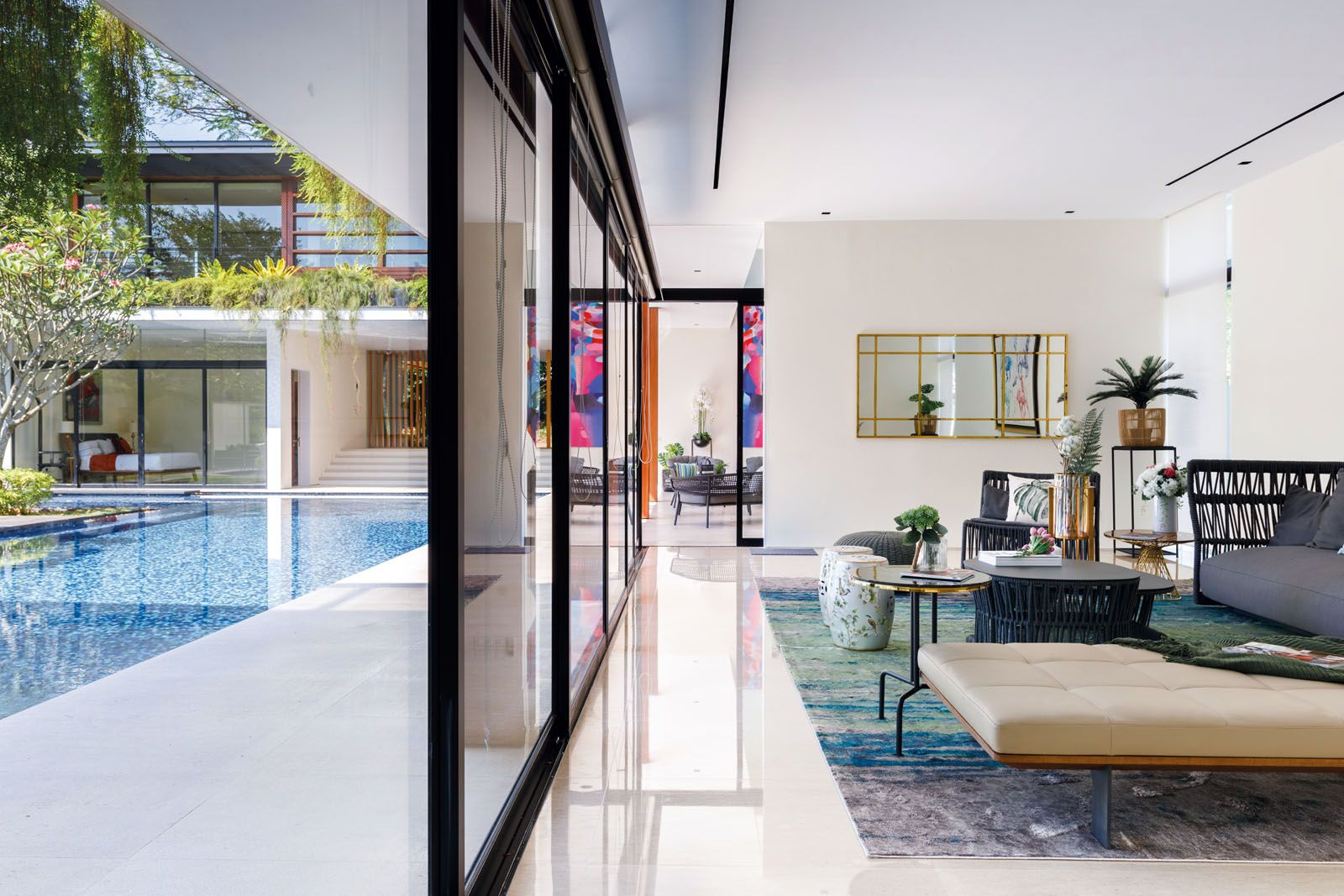 Strategically placed plants and the clever use of emerald tones in the living room draw the eye to the pool and the lush courtyard