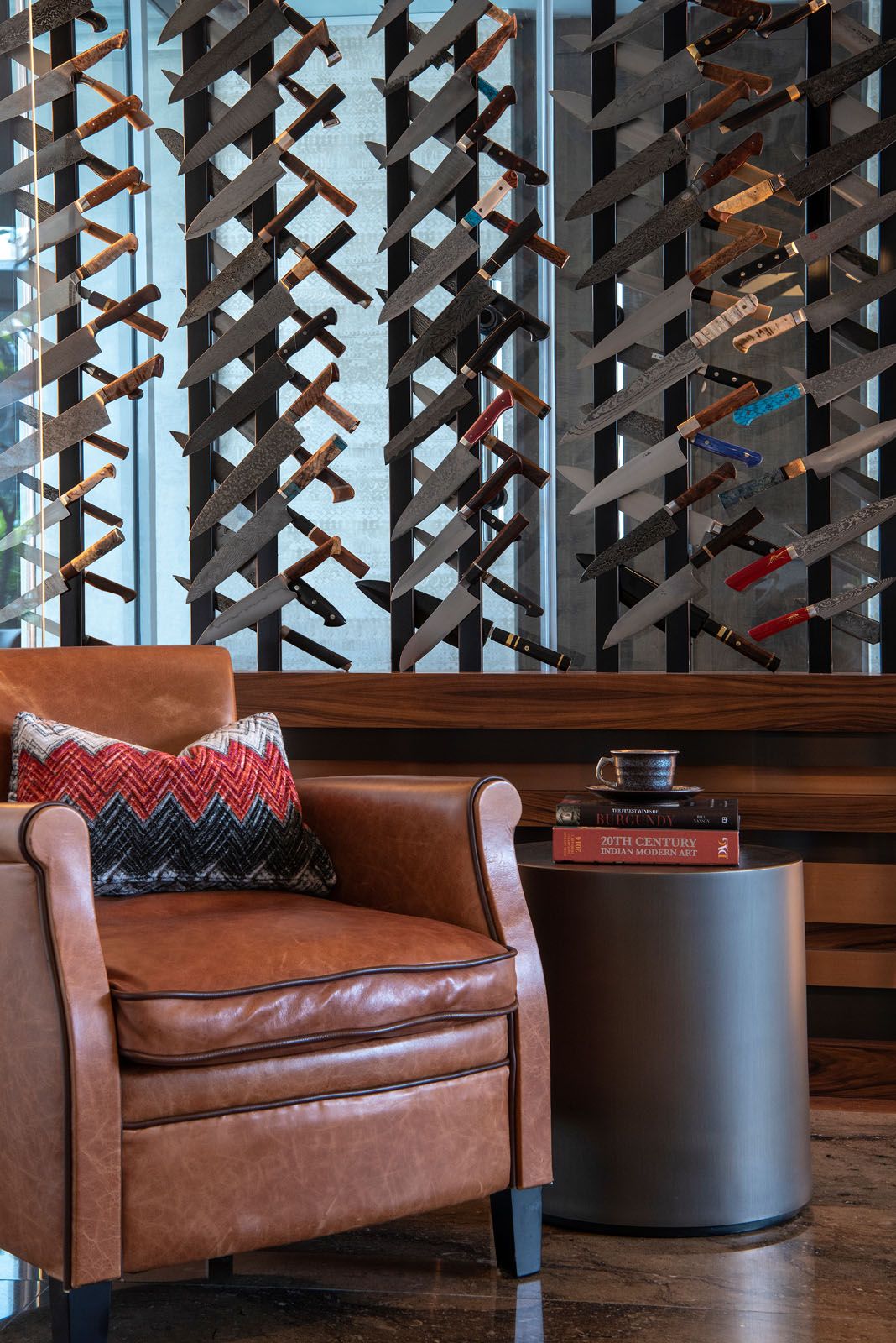 The glass display houses the owner's knife collection while separating the lounge area from the study