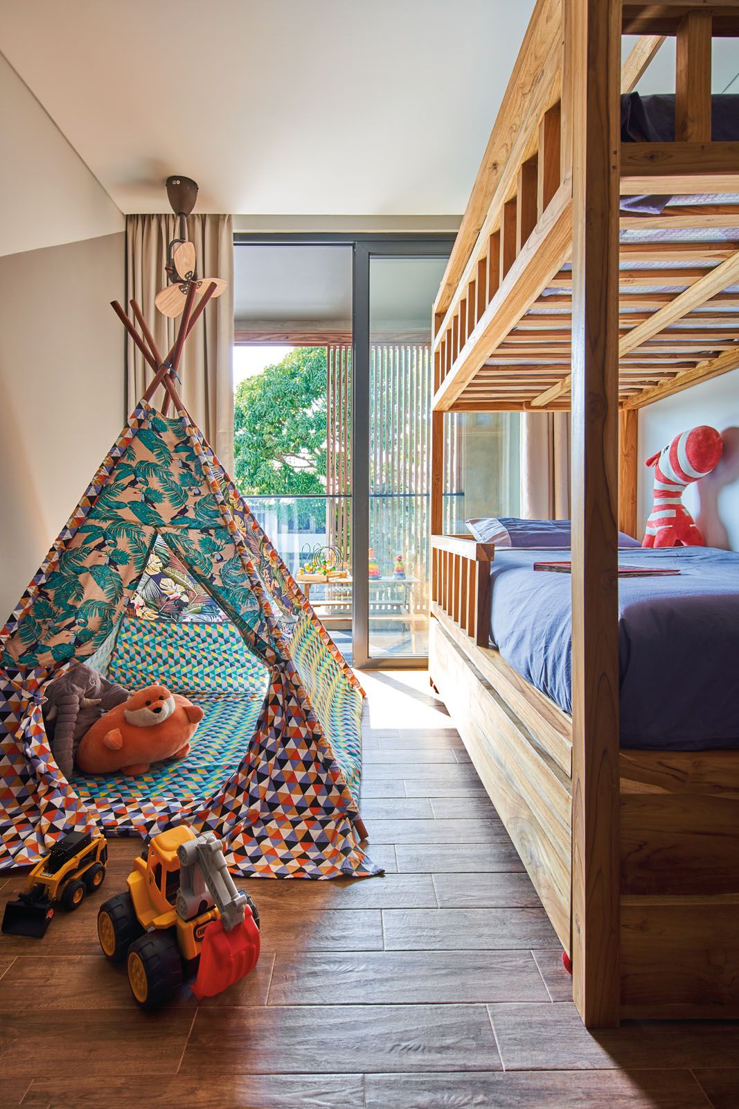 The children’s bedroom features wooden bunk beds and a vibrant play tent