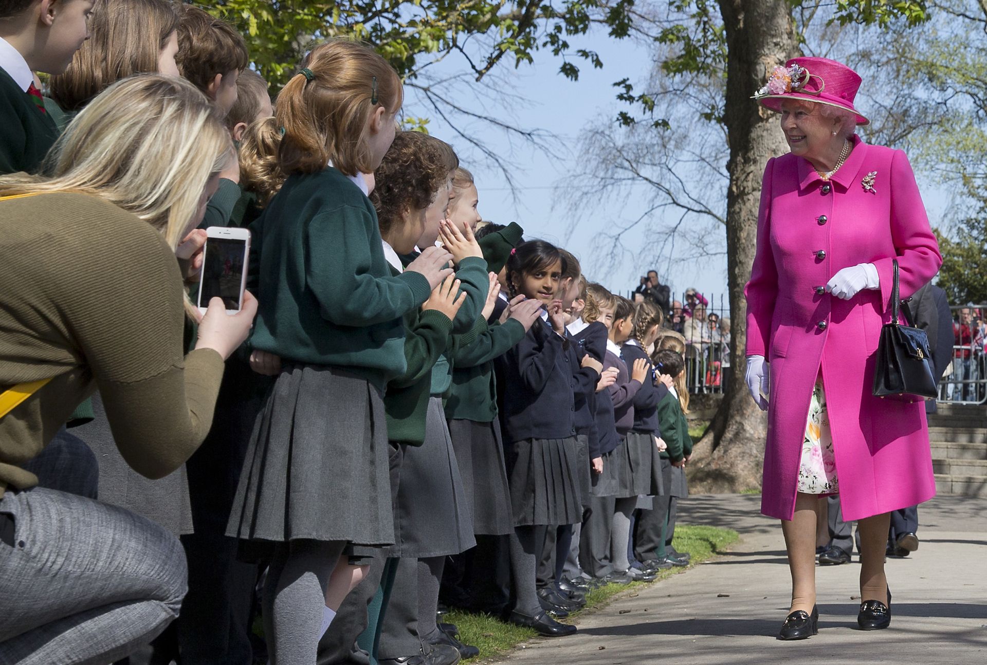 Britain's Queen Elizabeth II smiles as she is greeted by school children as she arrives to open a bandstand at Alexandra Gardens in Windsor, west of London, on April 20, 2016, the day before her 90th birthday.Queen Elizabeth II is set to celebrate her 90th birthday on April 21, with a family gathering and a cake baked by a reality television star, as a new poll finds Britain's longest serving monarch is as popular as ever. The queen has reigned for more than 63 years and shows no sign of retiring, even if