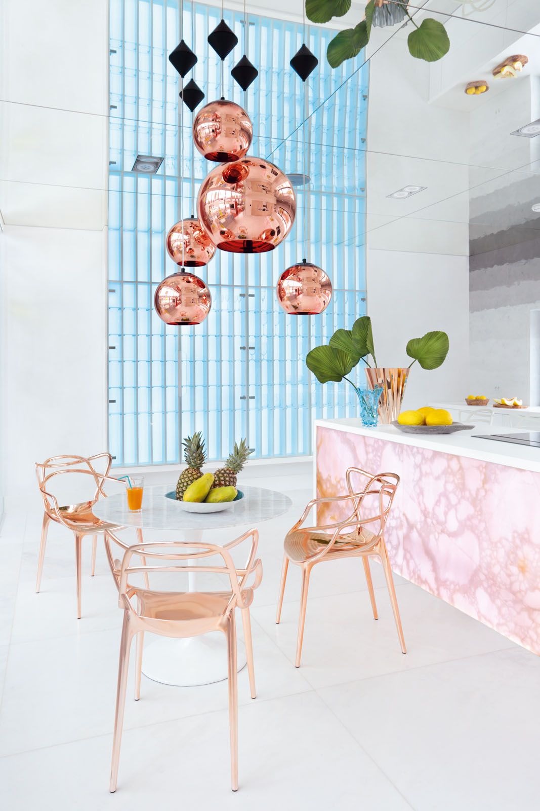 Glamorous pieces in the kitchen include the backlit stone island and metallic pieces such as the Tom Dixon Copper pendant lights and the Master chairs by Philippe Starck with Eugeni Quitlet for Kartell