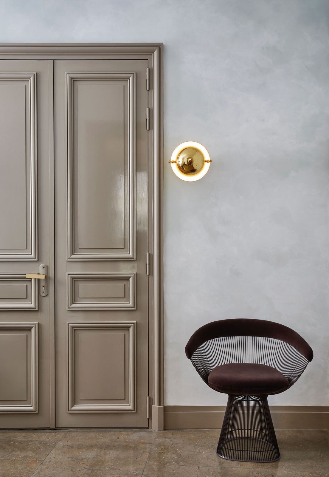 The entryway features a Knoll Platner chair and a vintage wall light