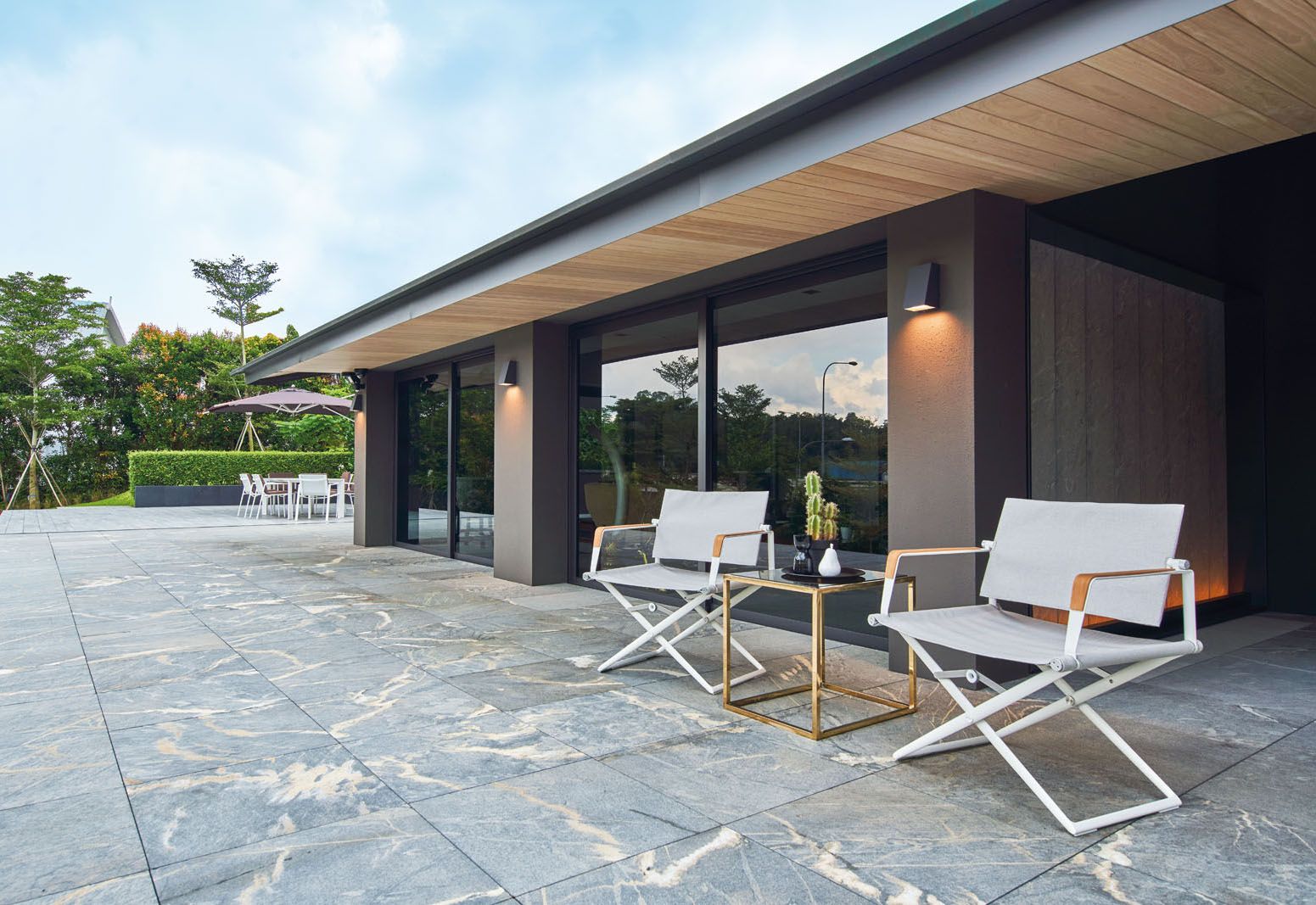 The patio features Dedon Seax armchairs, a Desalto Mac outdoor dining table, Kettal Park Life dining chairs and Classic Ocean Master umbrella