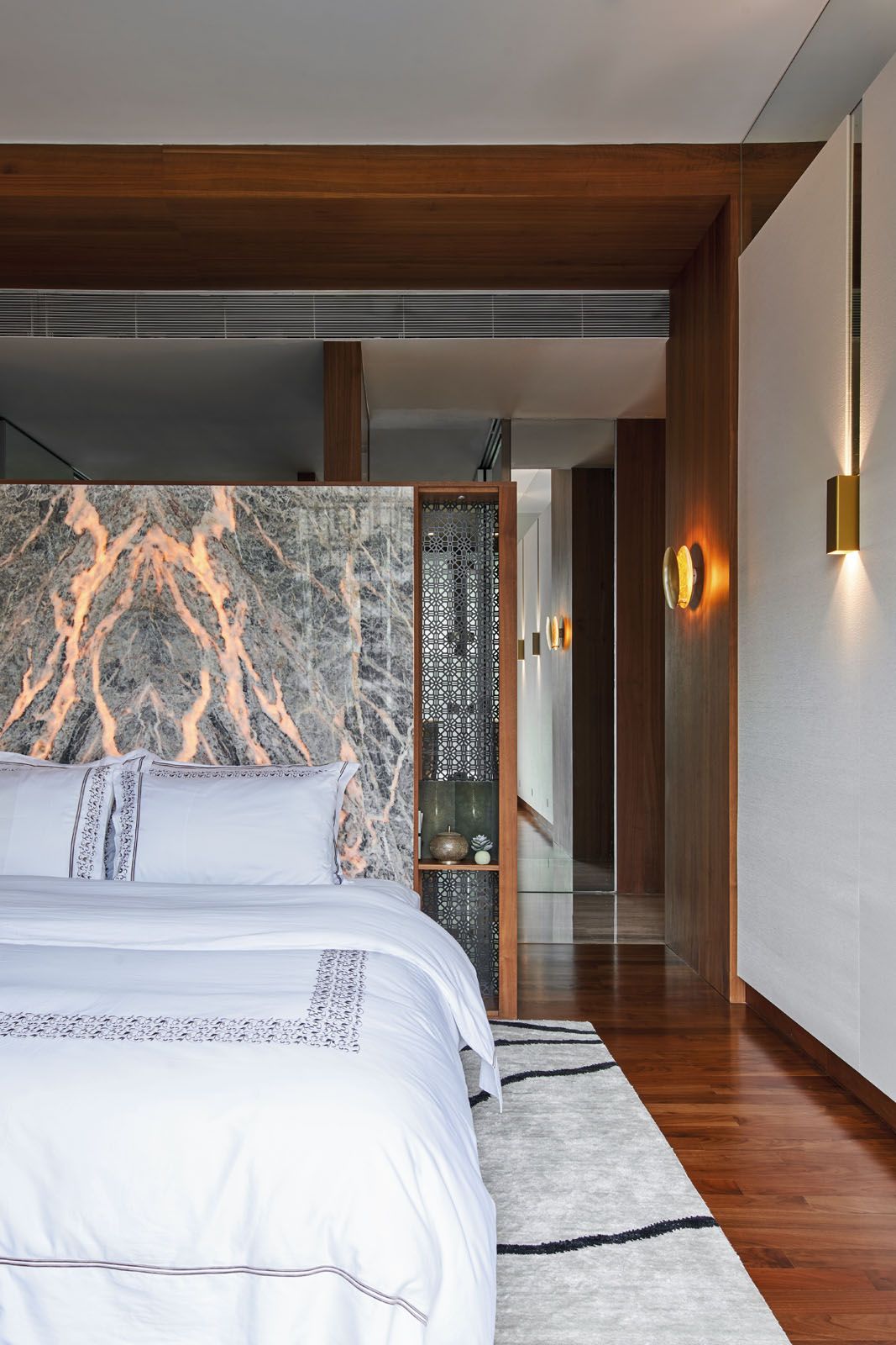 The custom-made headboard in the master bedroom features an onyx slab that lights up to showcase its beautiful veining