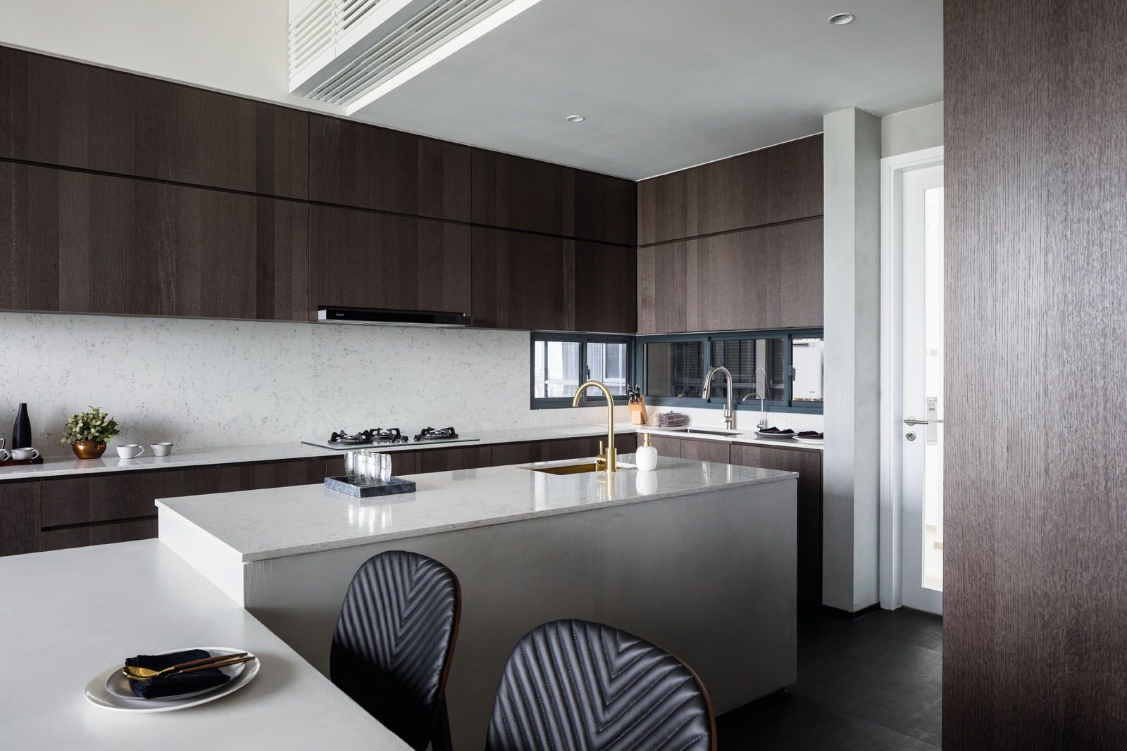 The centrepiece of the kitchen is an L-shaped island comprising a bar counter and dining table where the owners can entertain guests while they cook