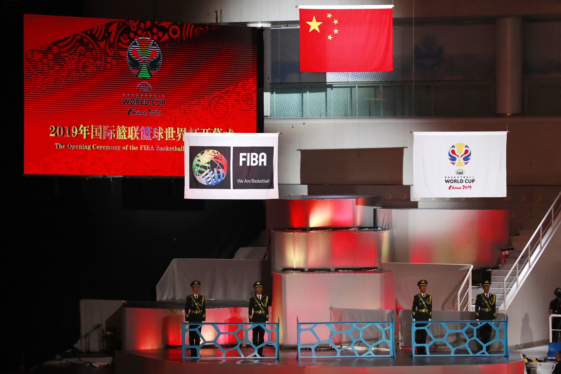 The Chinese national flag (C) is raised along with banners with the logos of the 2019 FIBA Basketball World Cup (R) and the International Basketball Federation (FIBA) during the opening ceremony of the 2019 Basketball World Cup in Beijing on August 30, 2019. (Photo by HOW HWEE YOUNG / POOL / AFP)