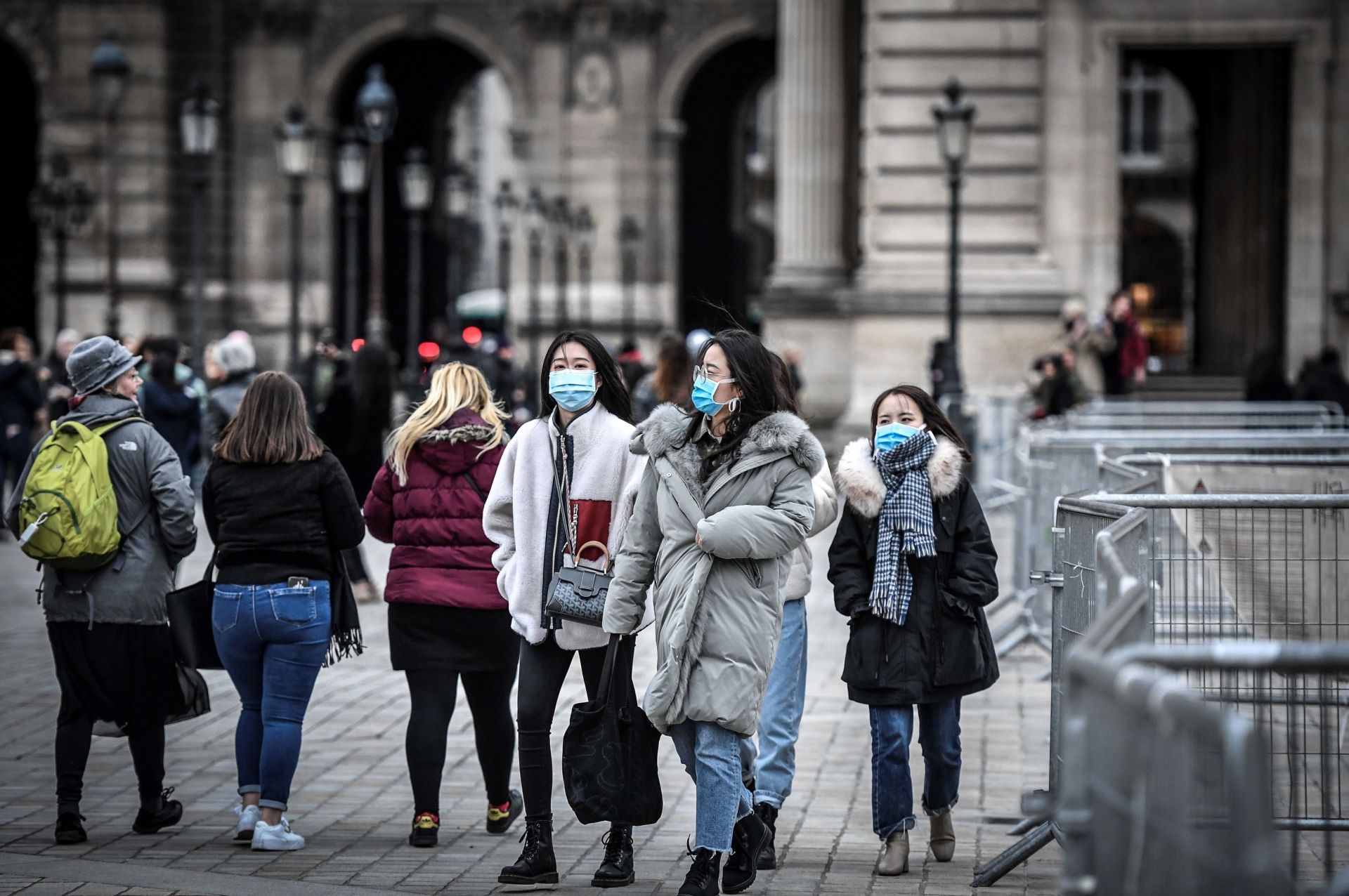 Tourists wearing a protective face mask amid fears of the spread of the COVID-19 novel coronavirus walk at the Pyramide du louvre area on February 28, 2020 in Paris. (Photo by STEPHANE DE SAKUTIN / AFP)