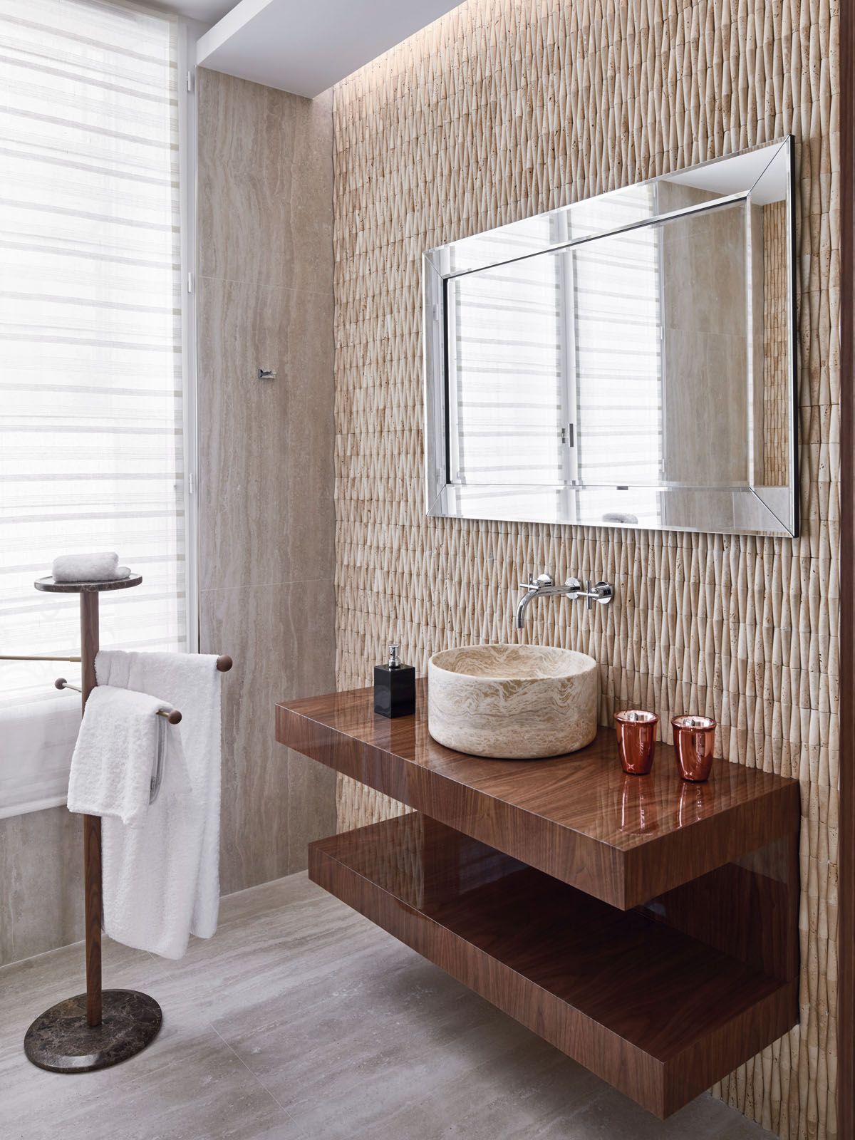 The travertine marquetry feature wall creates a tactile contrast against the polished walnut countertop and marble sink