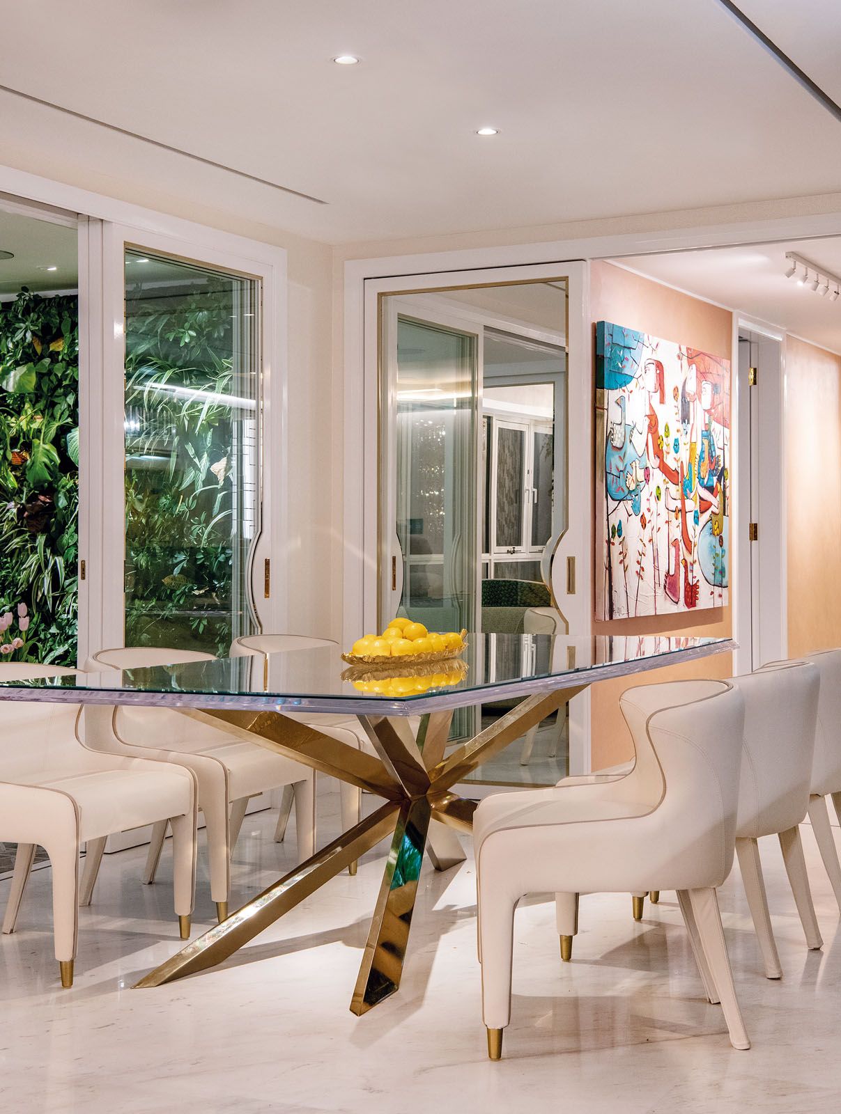 The sculptural dining table conveys a sense of lightness while matching the gold hardware found on the doors and furnishings