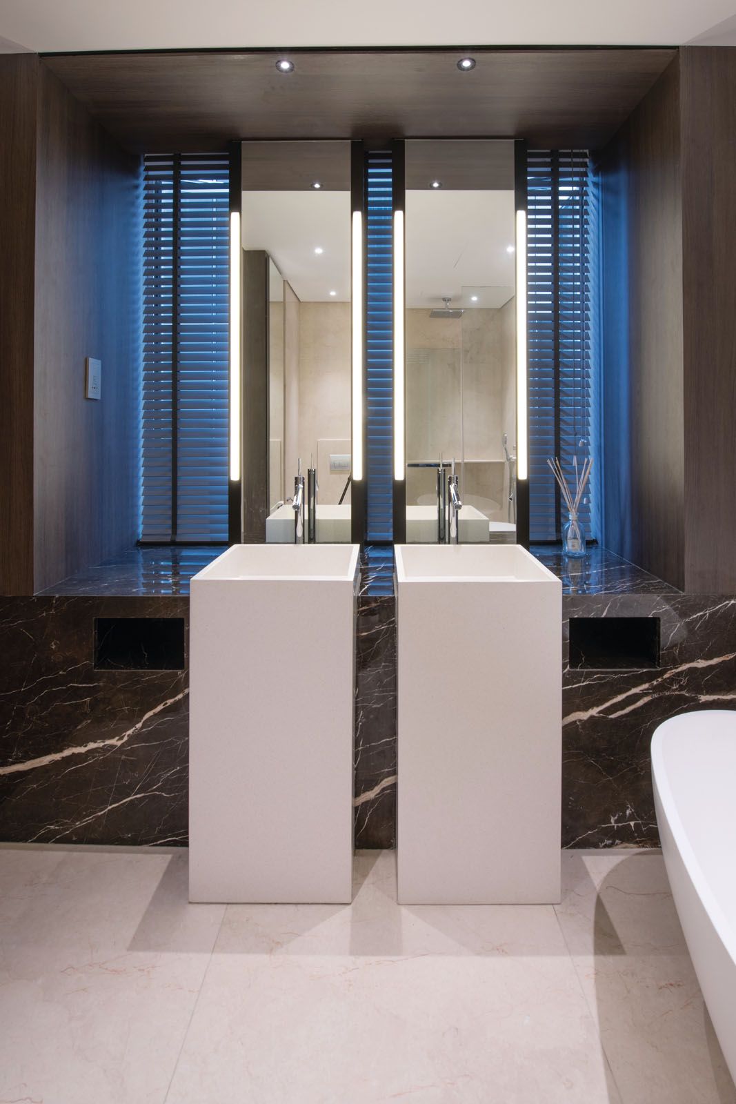 The sinuous veins of the marble counter add a dramatic flair to the minimalist bathroom