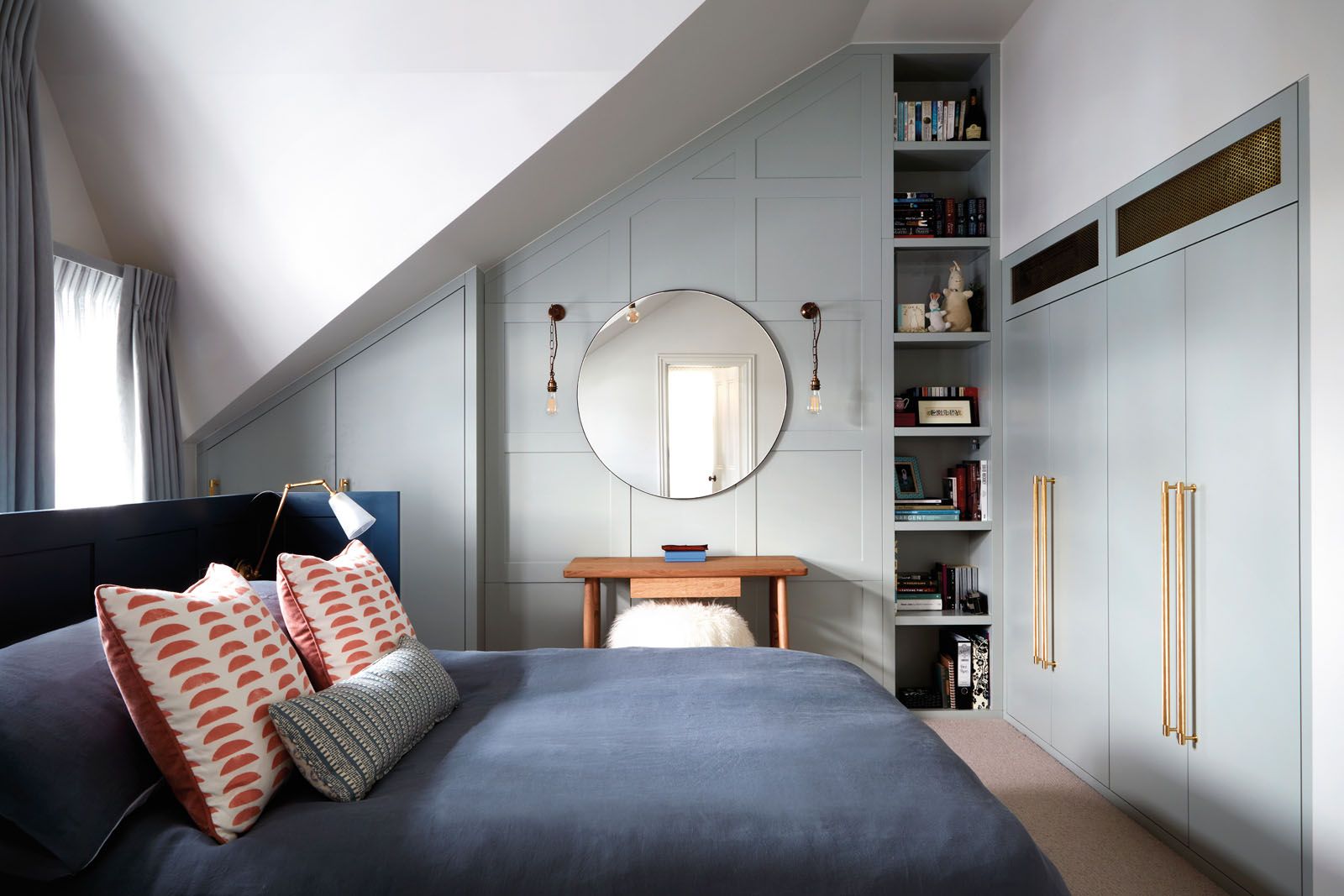 Coral accent cushions and a furry stool add a playful touch to a blue bedroom