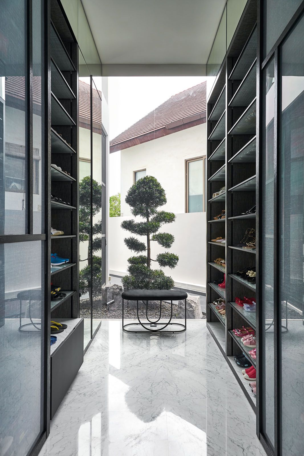 Bronze-tinted mirrored panels add a touch of glamour to the hallway while storage areas conceal the awkward corners of the site; the walk-in shoe cabinet frames the sight of the Japanese bonsai tree in the garden