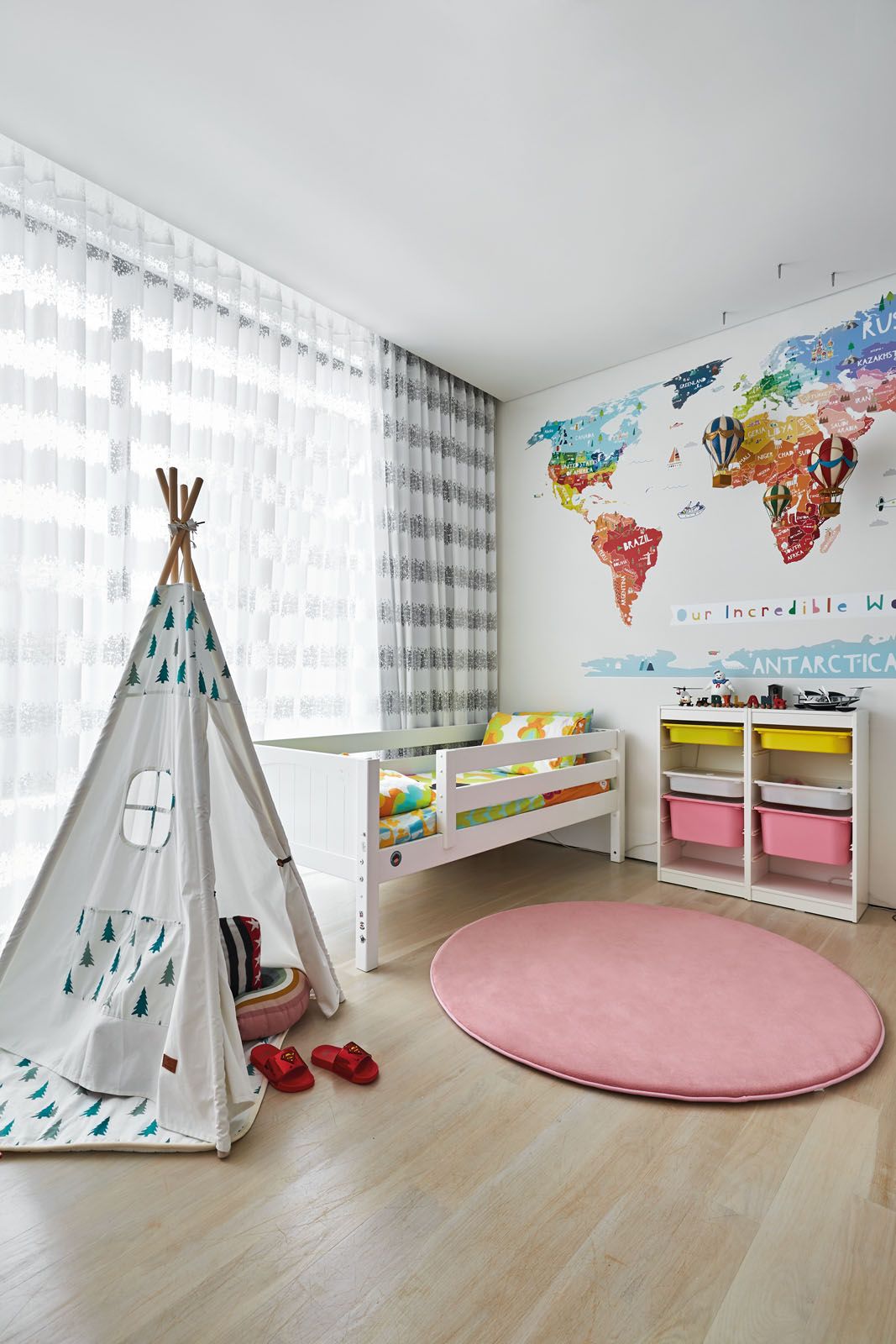 The colourful wall mural depicting a world map is the centrepiece of the children’s bedroom