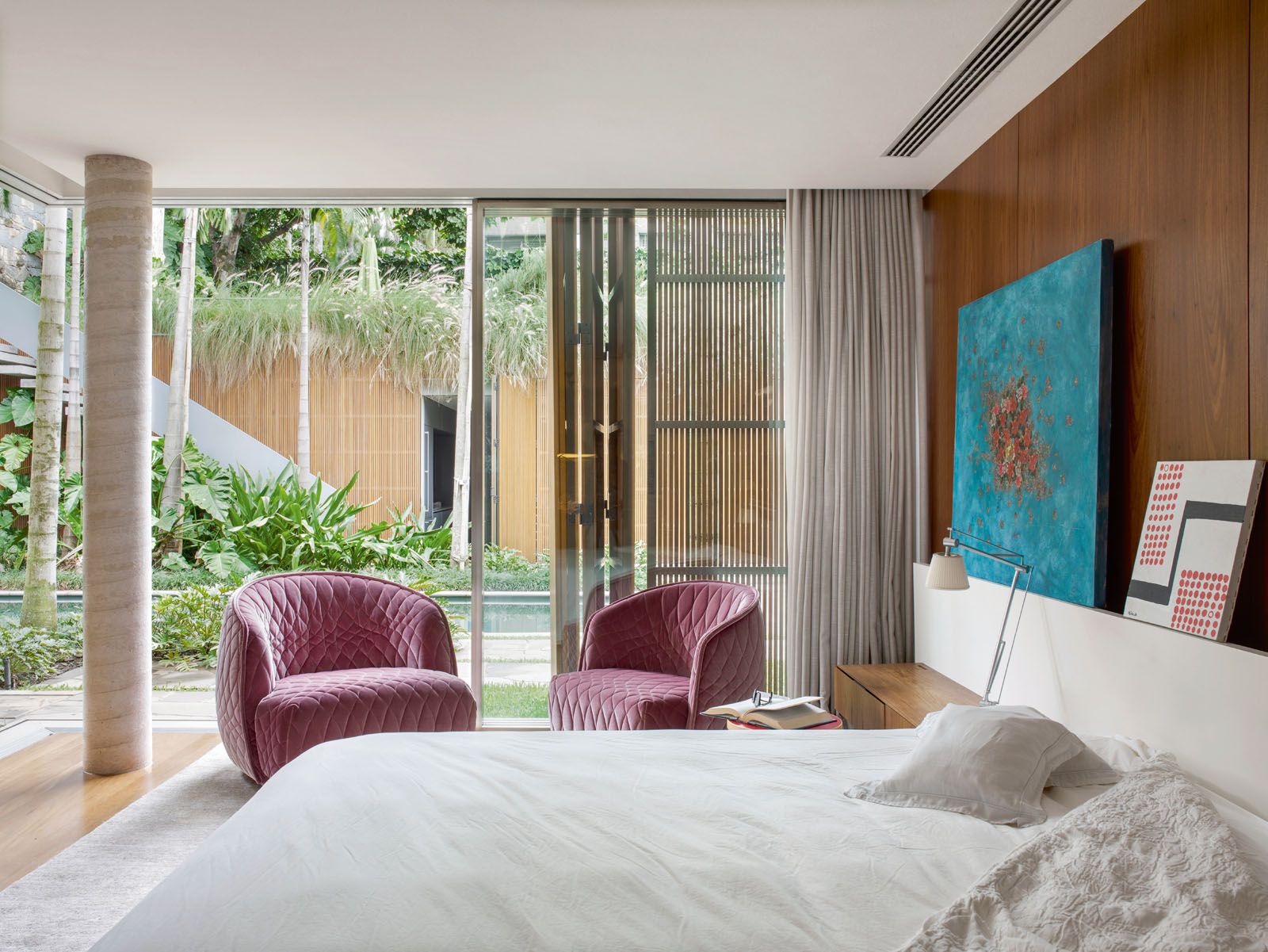 A pair of violet armchairs brings a pop of colour to the master bedroom