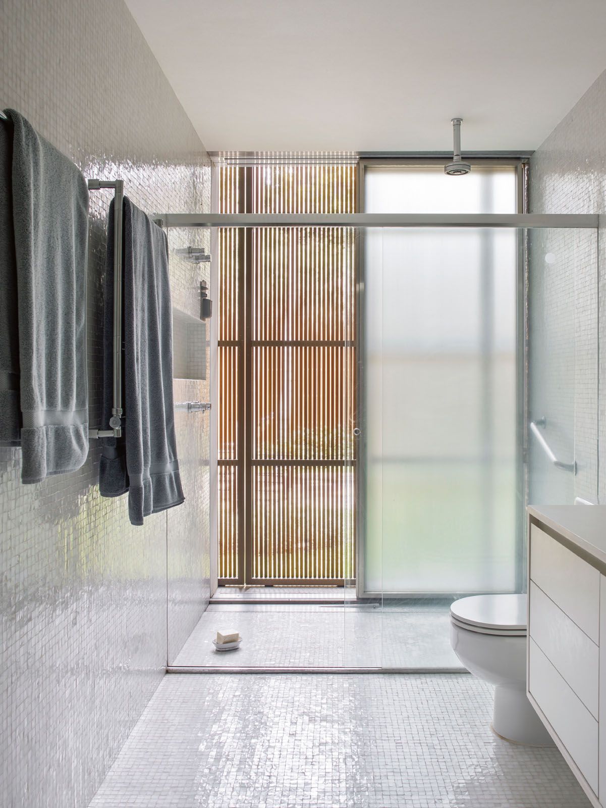 This minimalist bathroom features white square tiles on the wall and floor
