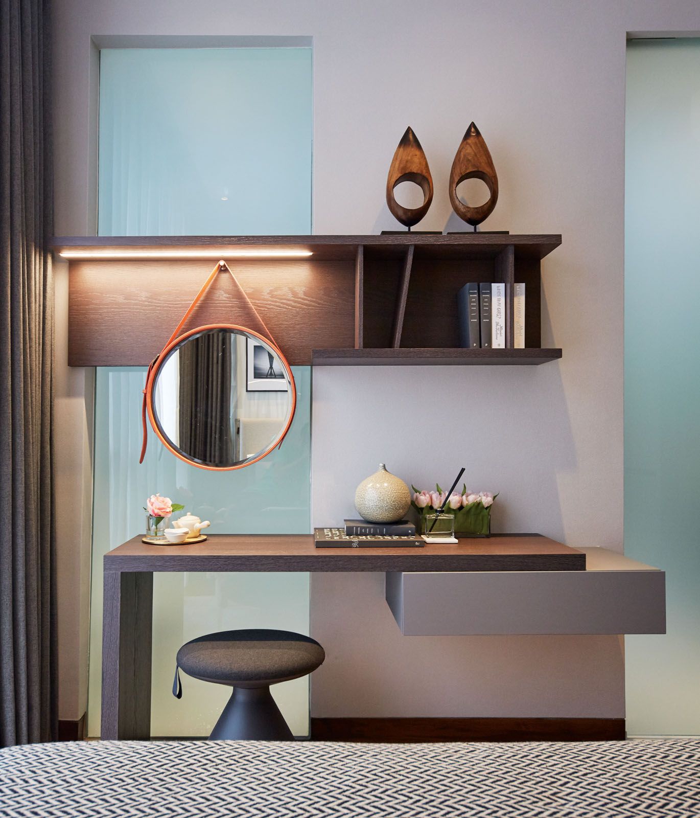 The circular mirror echoes the rotund seat and decor items at the desk area in the junior master bedroom