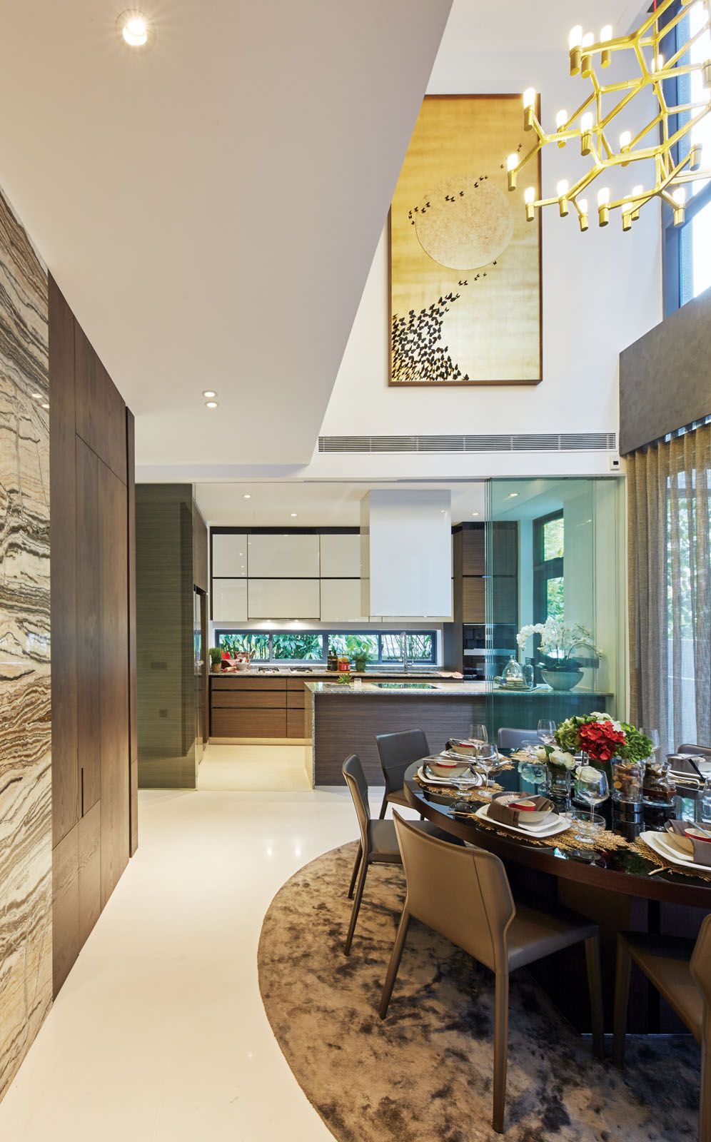 A gold artwork and the Nemo Crown Major chandelier draw the eye upwards to the grand height of the dining room